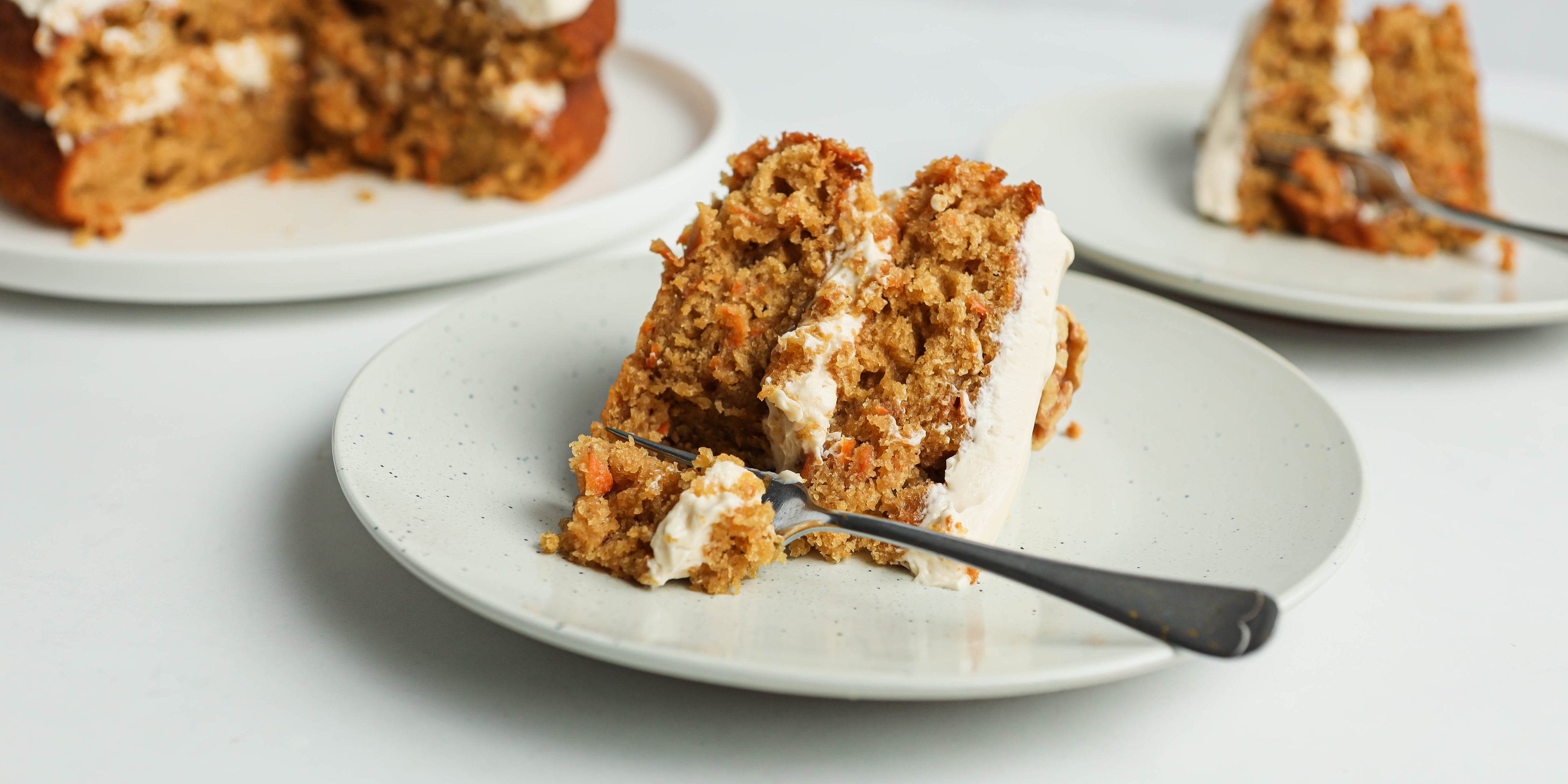 Close up of a slice of Classic Carrot Cake on a plate with a fork cutting into it 