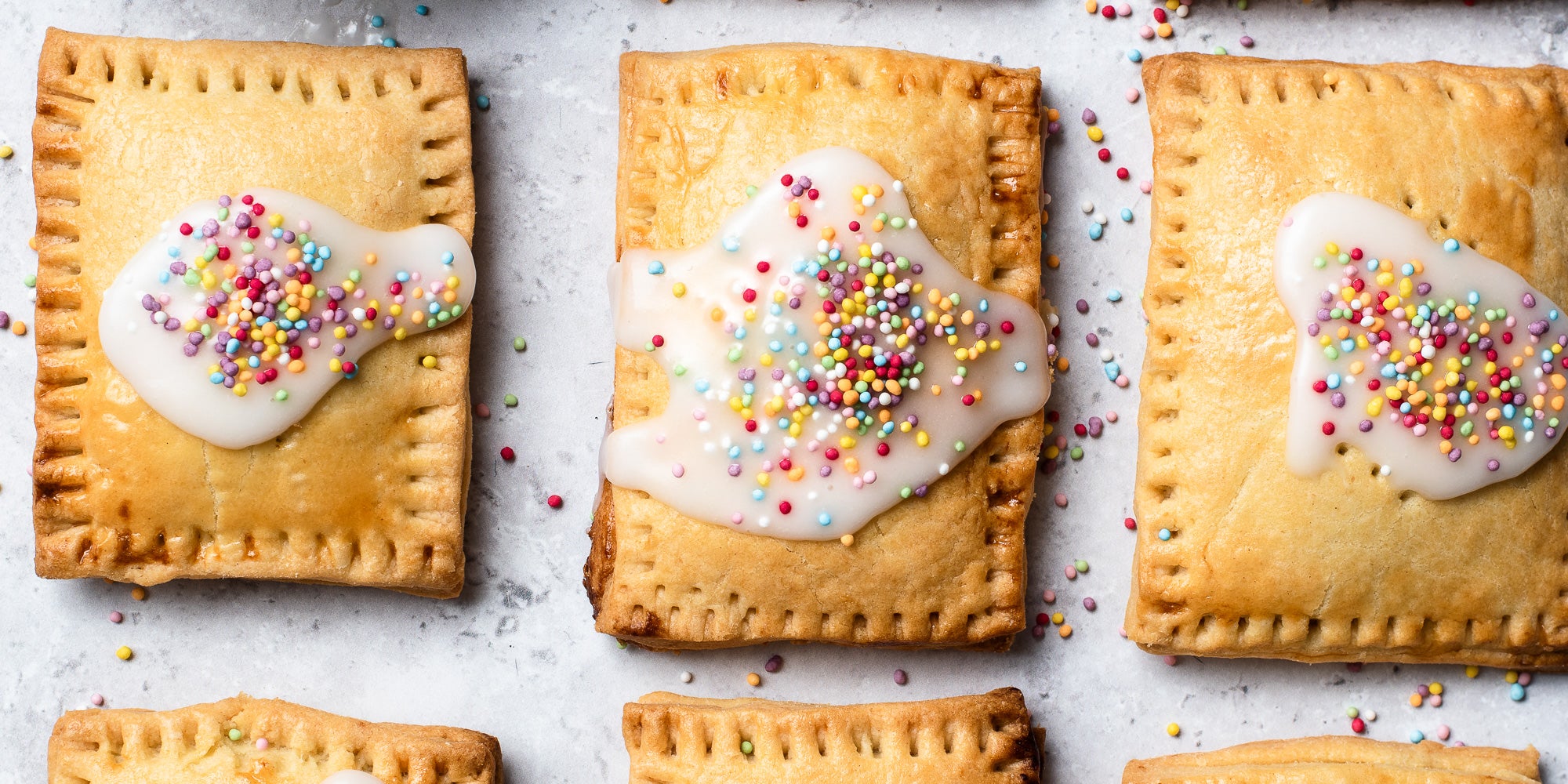 Overhead shot of  3 Pop Tarts with white icing and sprinkles.