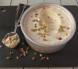 Scoop of pistachio ice cream next to a tub of homemade pistachio ice cream