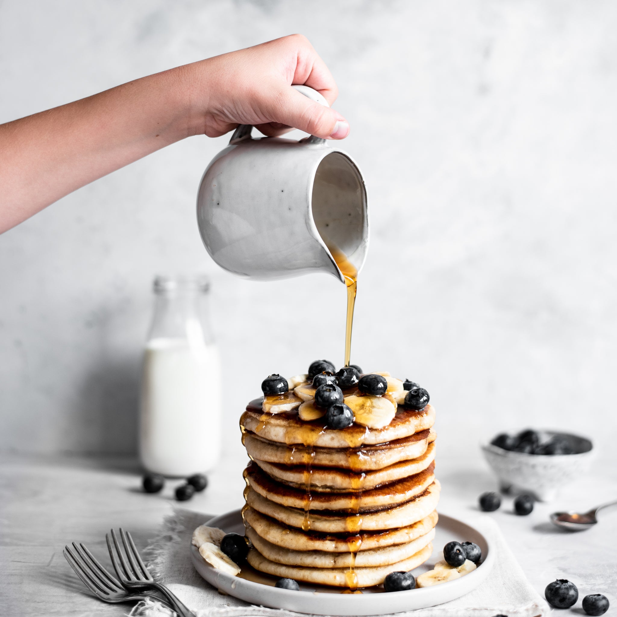 Pouring golden syrup over a stack of vegan pancakes