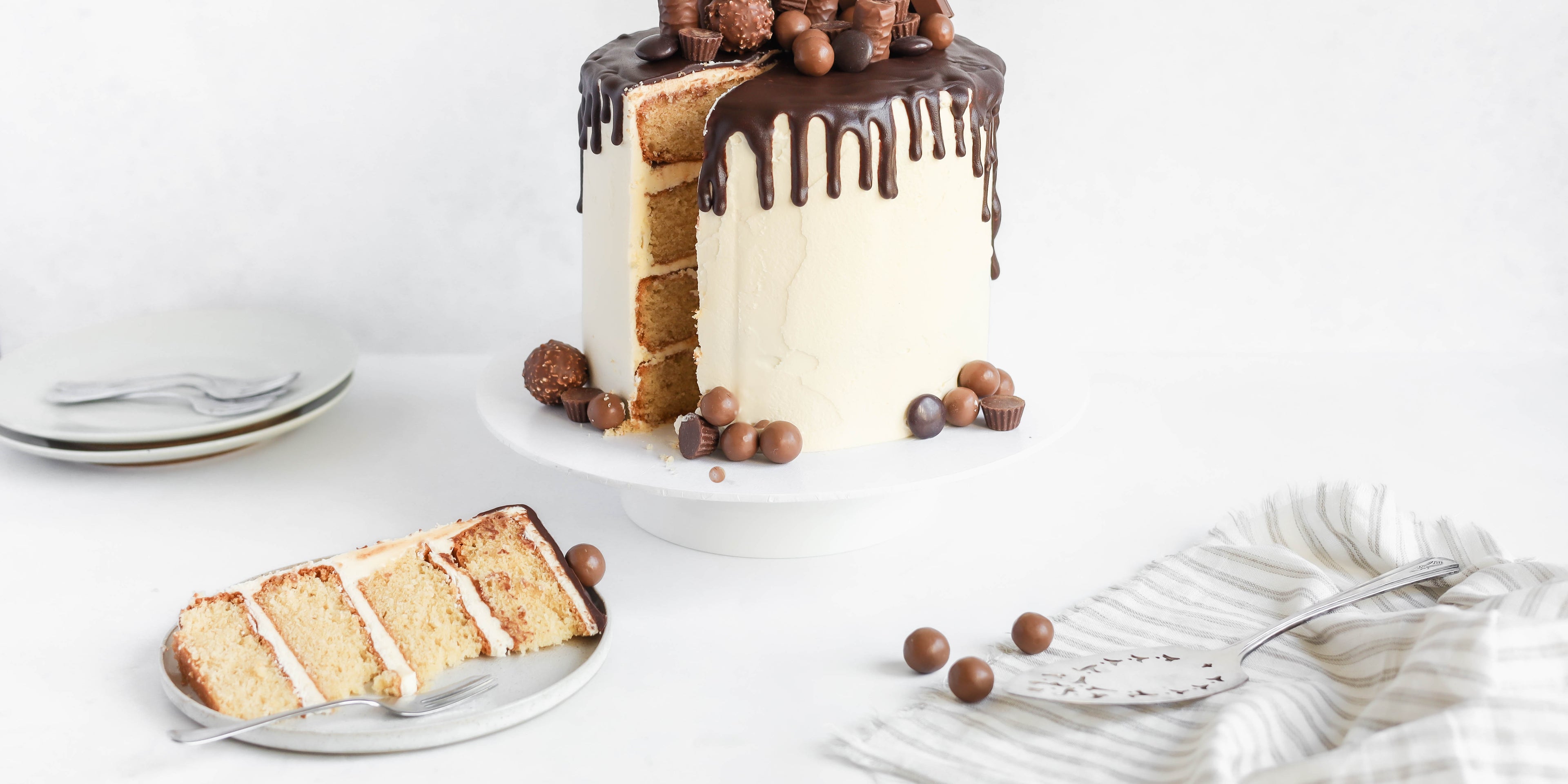 Ultimate Birthday Drip Cake with a slice cut out, showing all four delicious layers. Dripped with melted chocolate