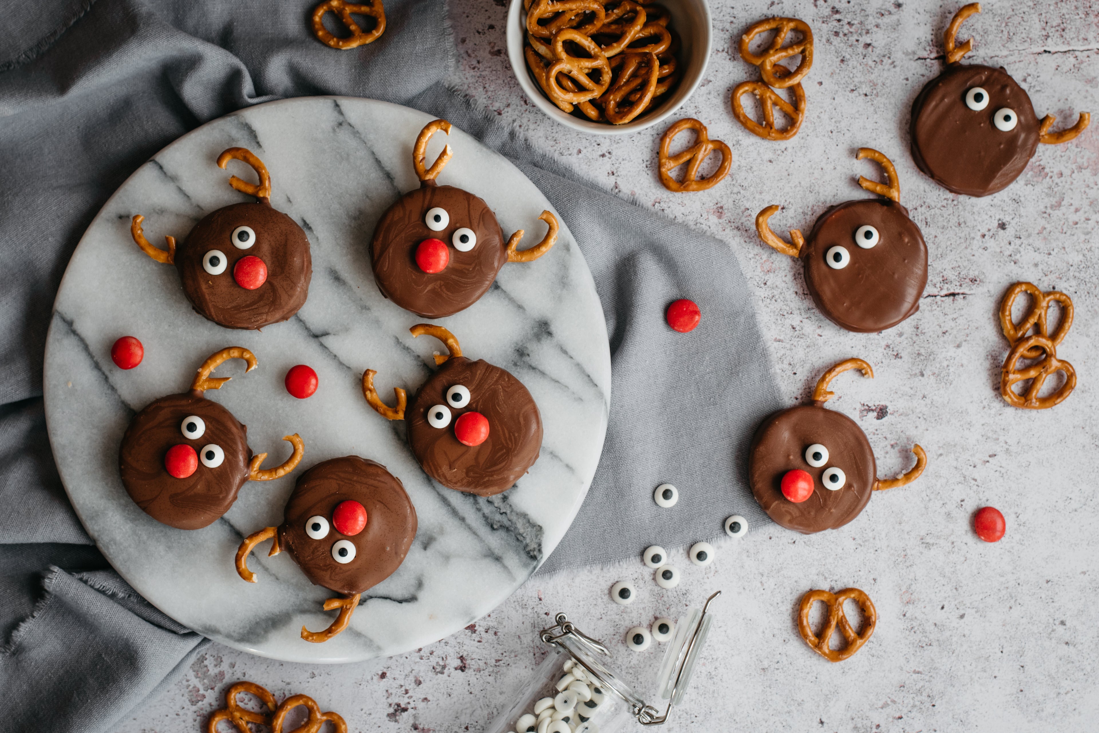 Top view of Reindeer Orange Creams decorated with broken pretzels and icing eyes on a marble serving board