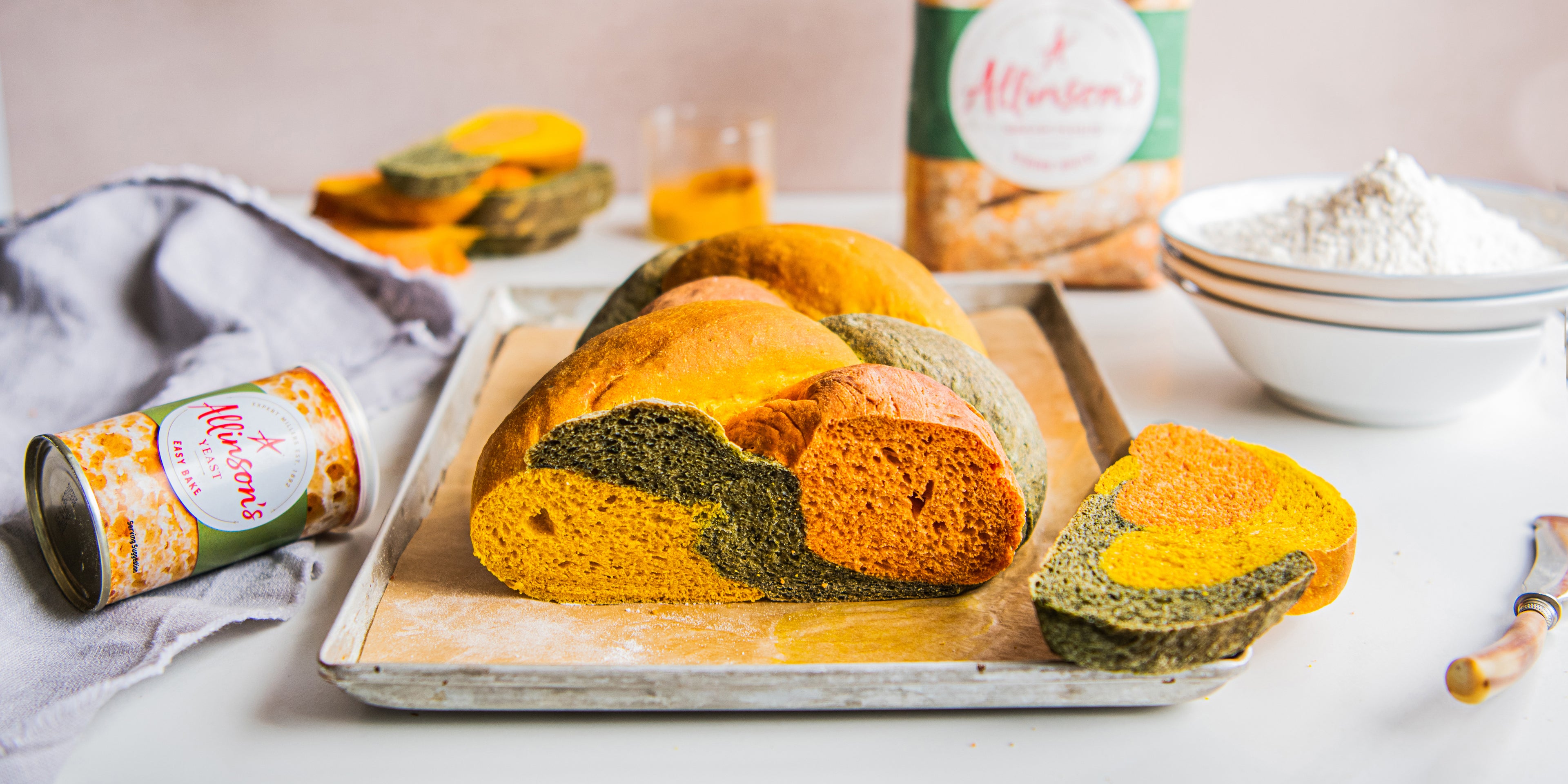 Side on view of a plaited tri colour loaf on a baking tray