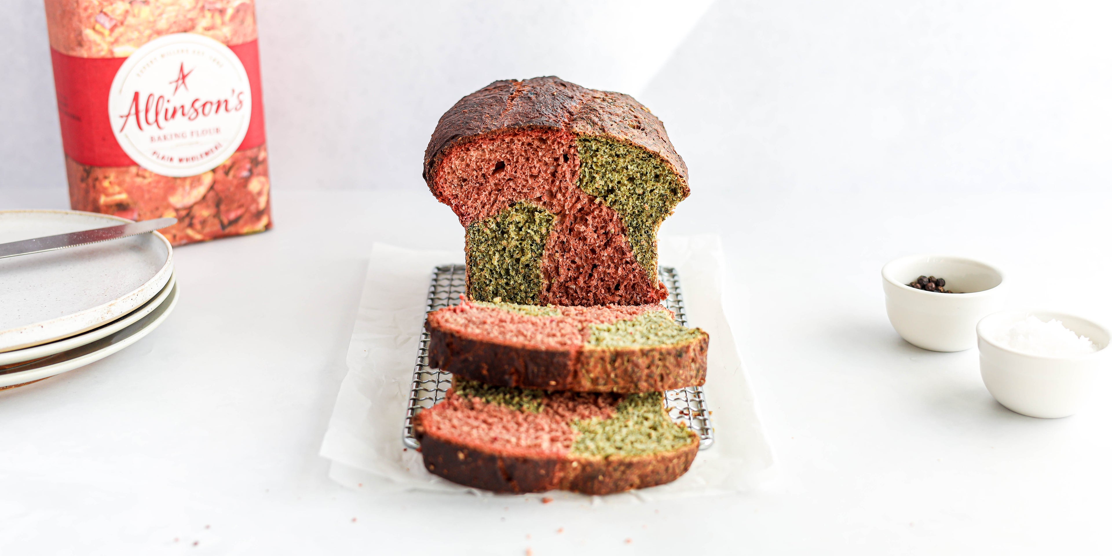 Marble Vegetable Bread cut on a wire rack, showing the pink and green inside. Bag of Allinson's flour in the background