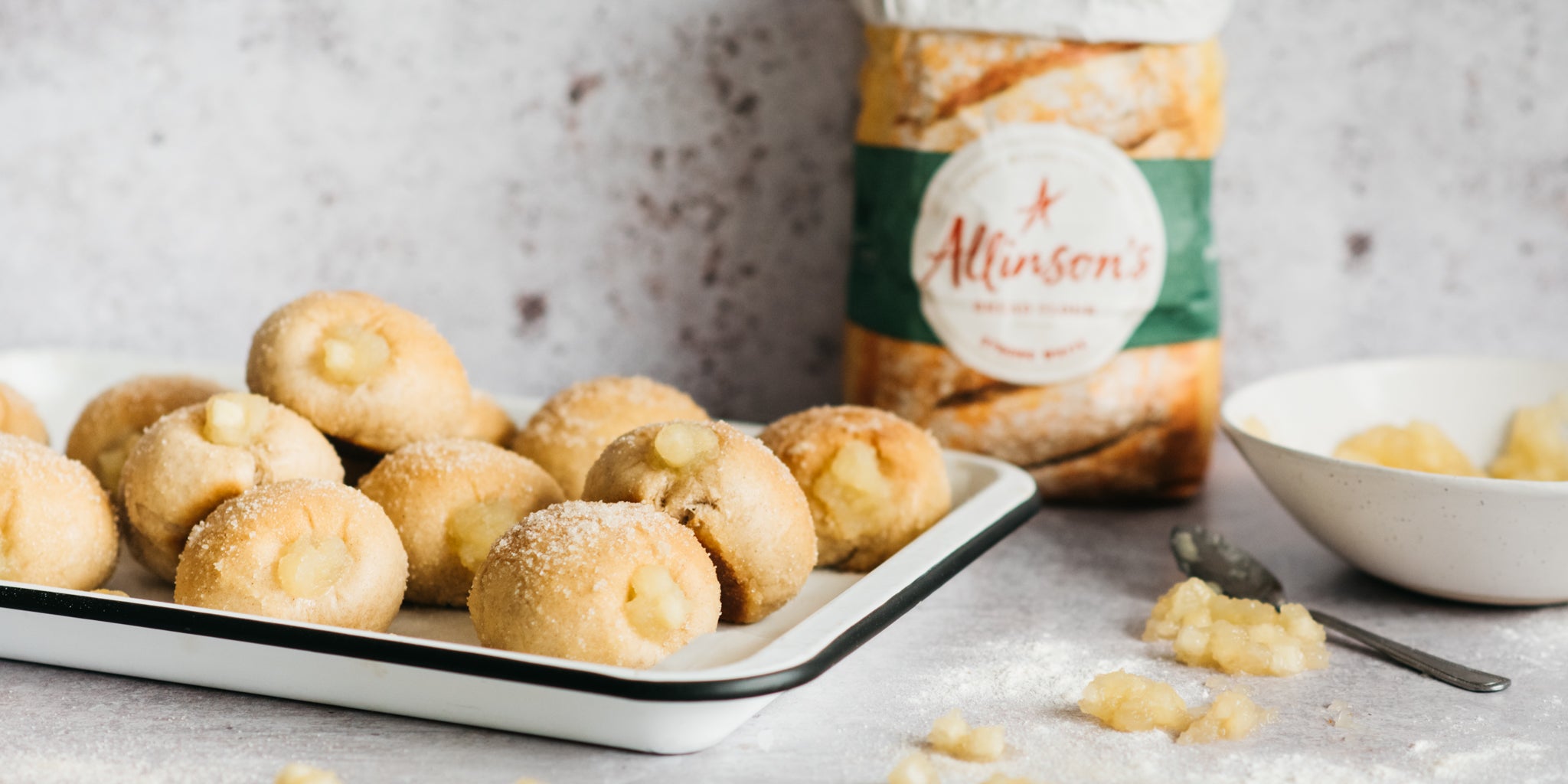 Baking tray of apple doughnuts with pack of flour in background