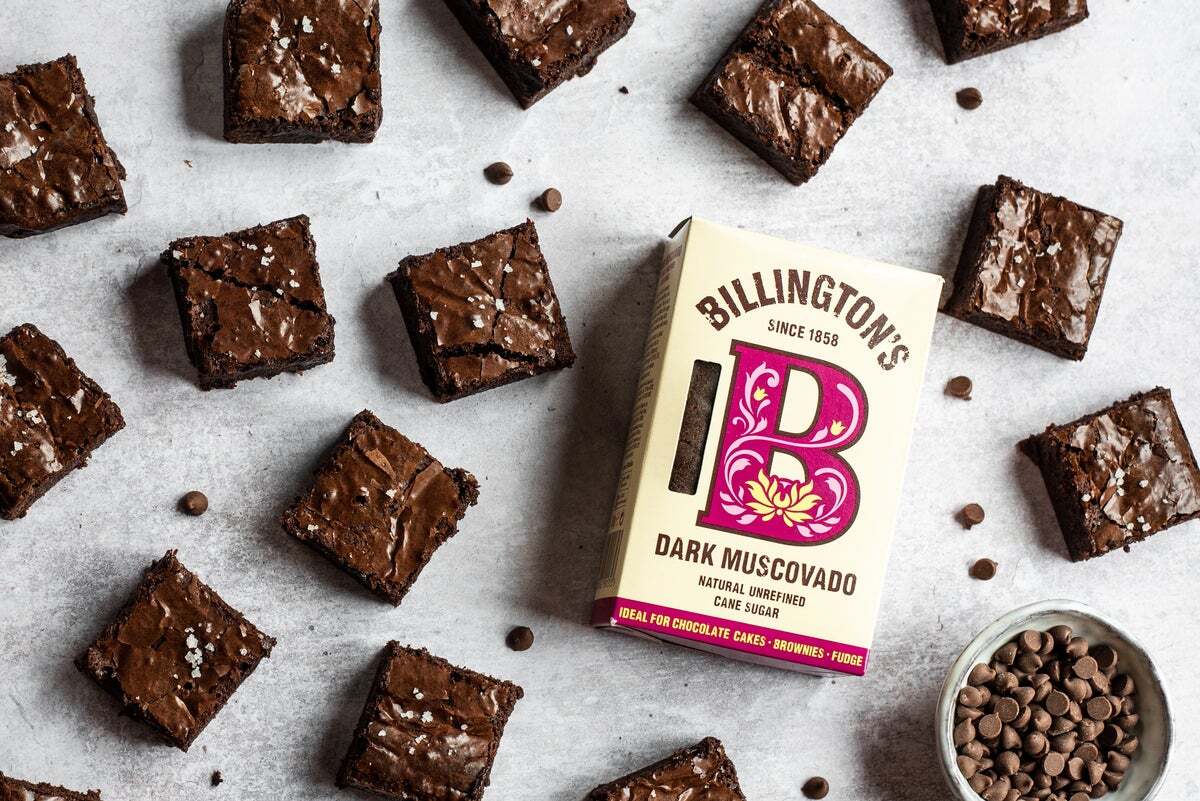 Chocolate brownies dusted with sea salt sitting next to a box of Billington's Dark Muscovado sugar