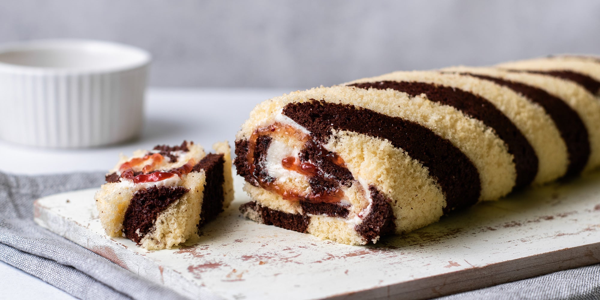 Close up Chocolate & Vanilla Swiss Roll with a slice cut out, showing the raspberry jam filling