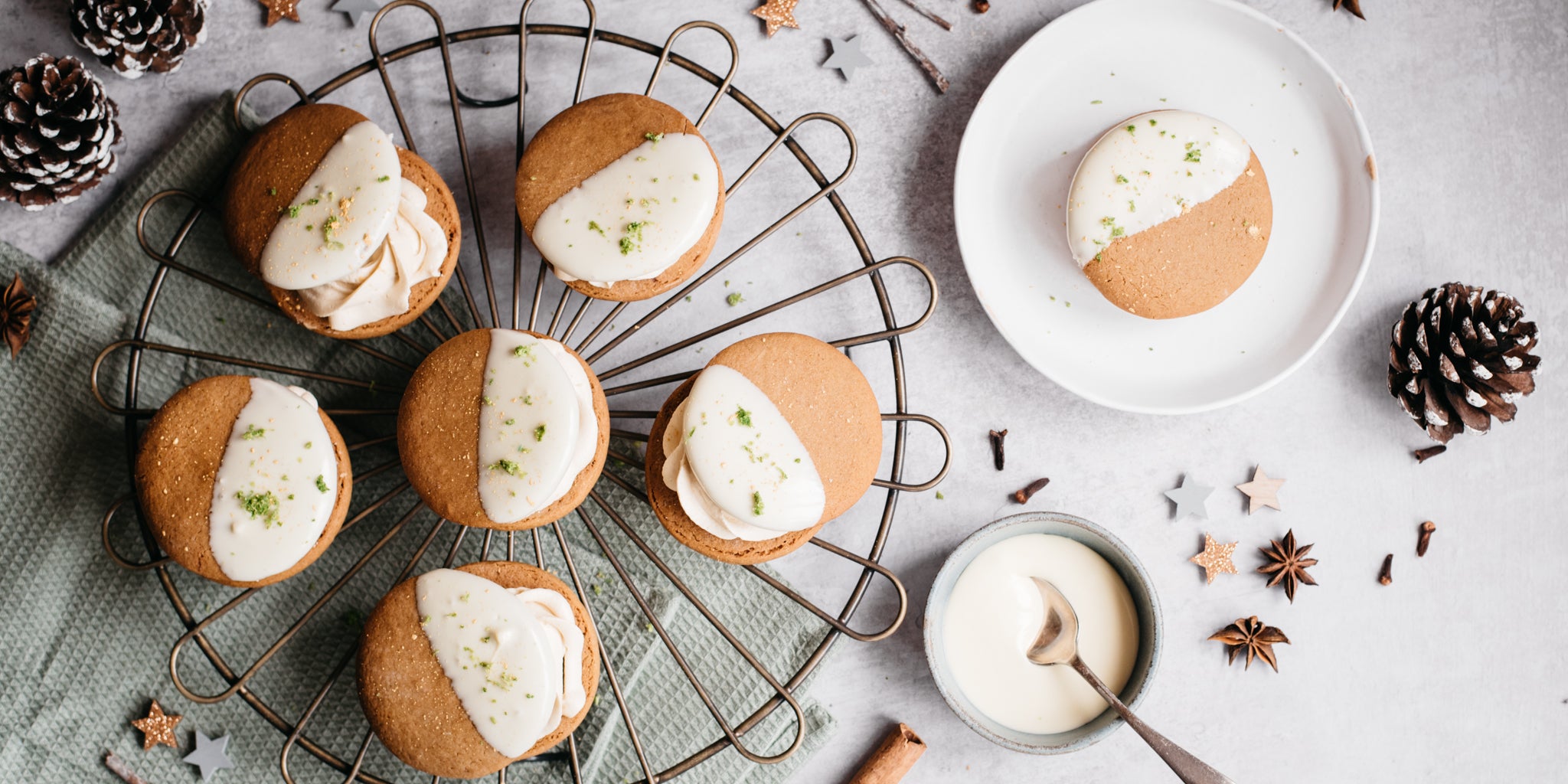 Top view of Citrus Gingerbread Cookies dipped in dairy free white chocolate next to pine cones and star anise