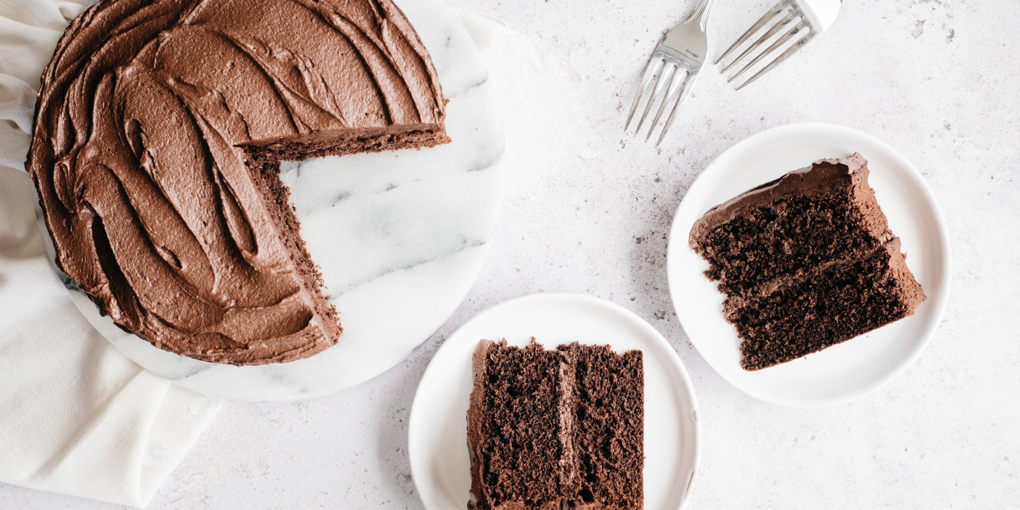 Top down shot of chocolate cake with two slices removed and two forks
