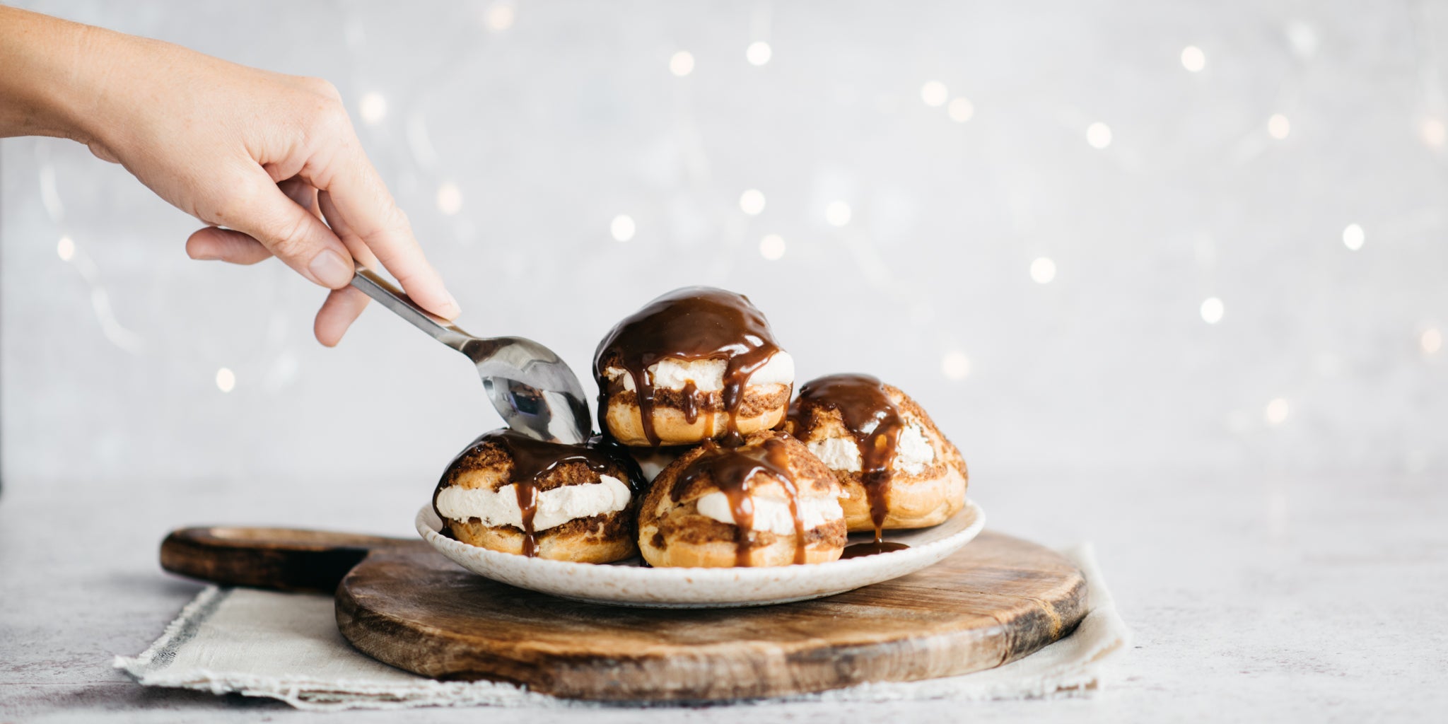Hand reaching in with a spoon to take a bite of the profiteroles