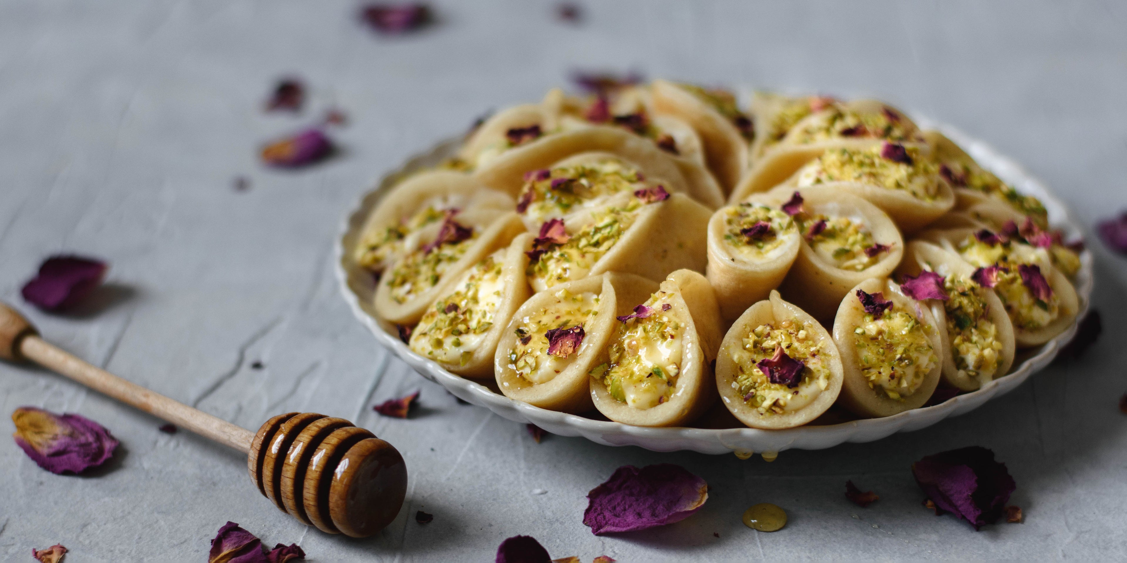 Plate of Qatayef with honey drizzler and petals