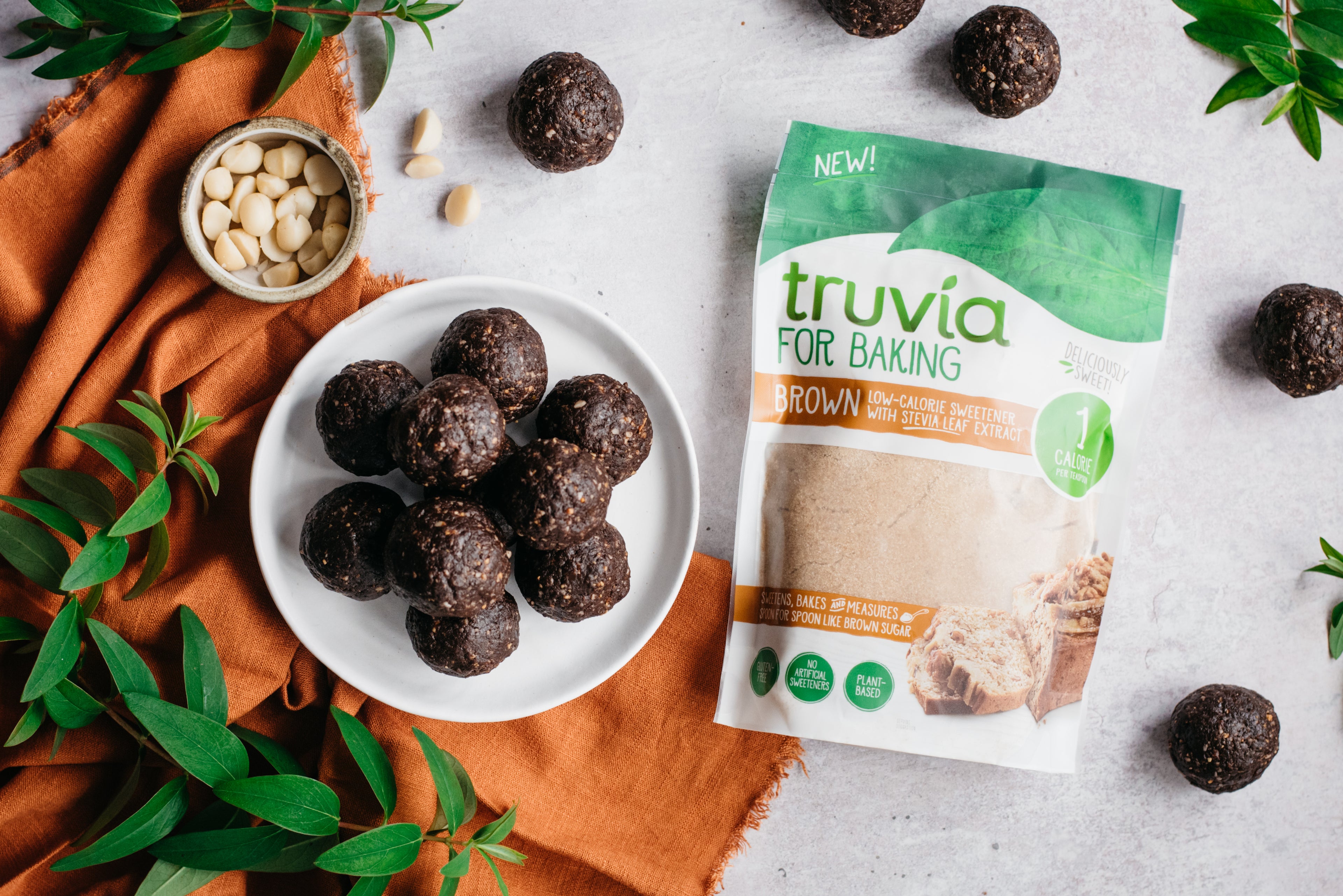 Top down view of a plate of raw vegan energy balls next to a pack of truvia for baking brown