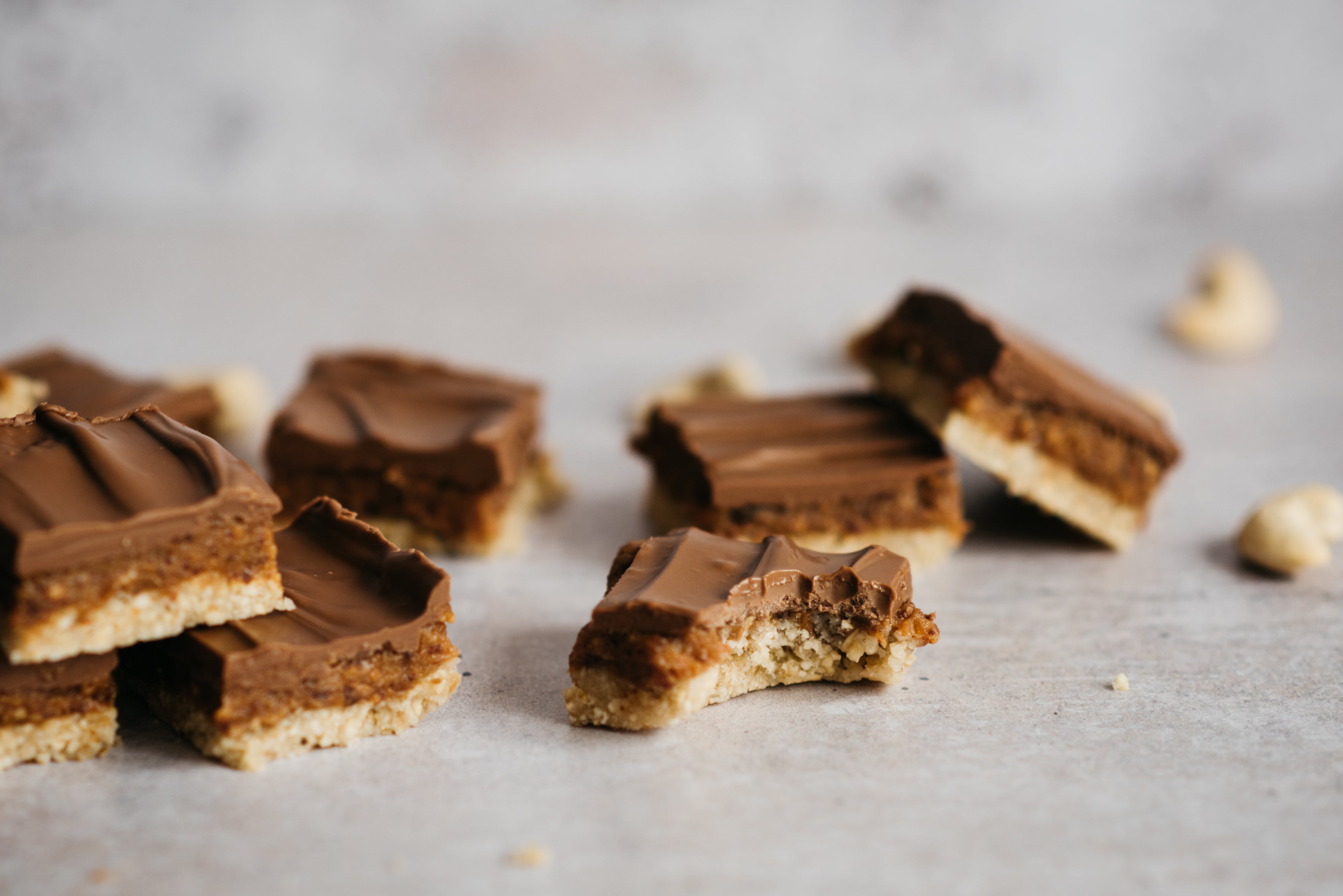 Close up of No-Bake Millionaire Squares with a bite taken out of one of the slices