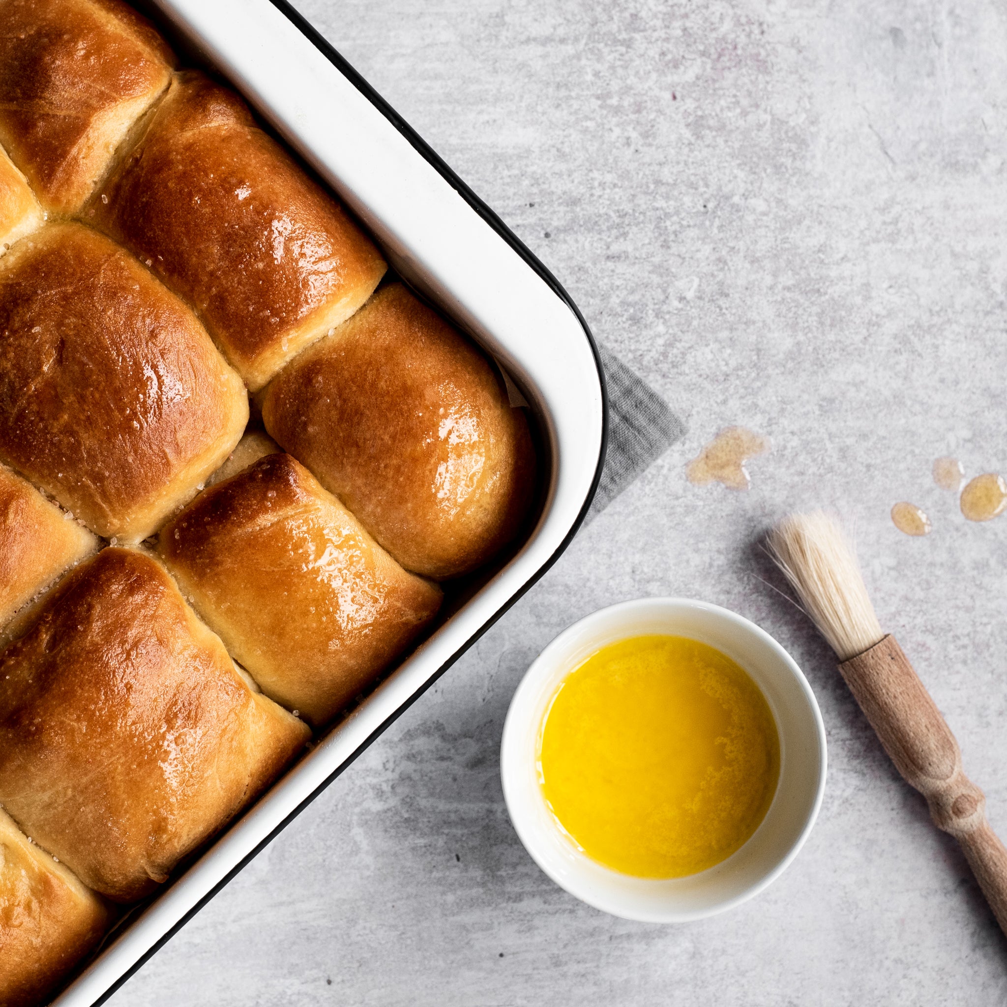 bread rolls in a baking tin with a side of melted butter