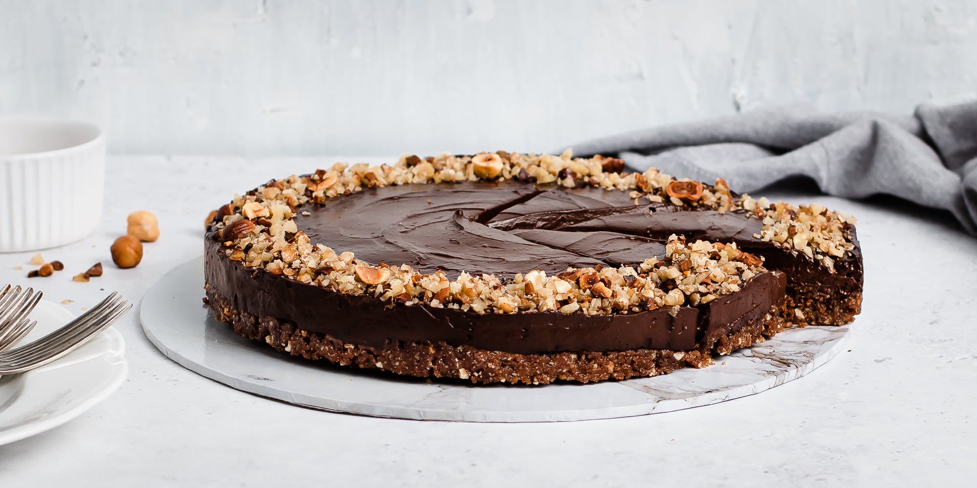 Raw Chocolate Avocado Cheesecake with a slice cut out on a marble serving board