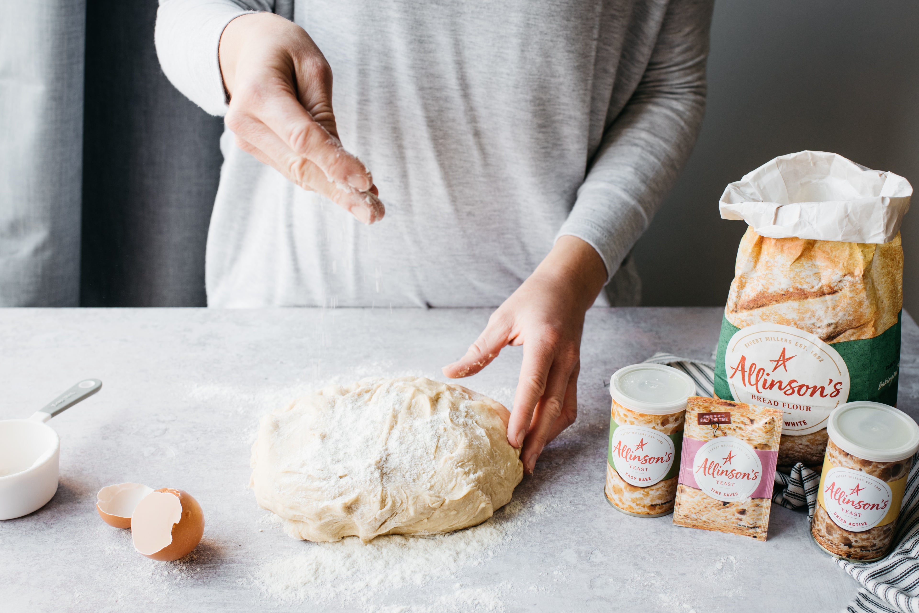 Hand sprinkling flour on top of bread dough