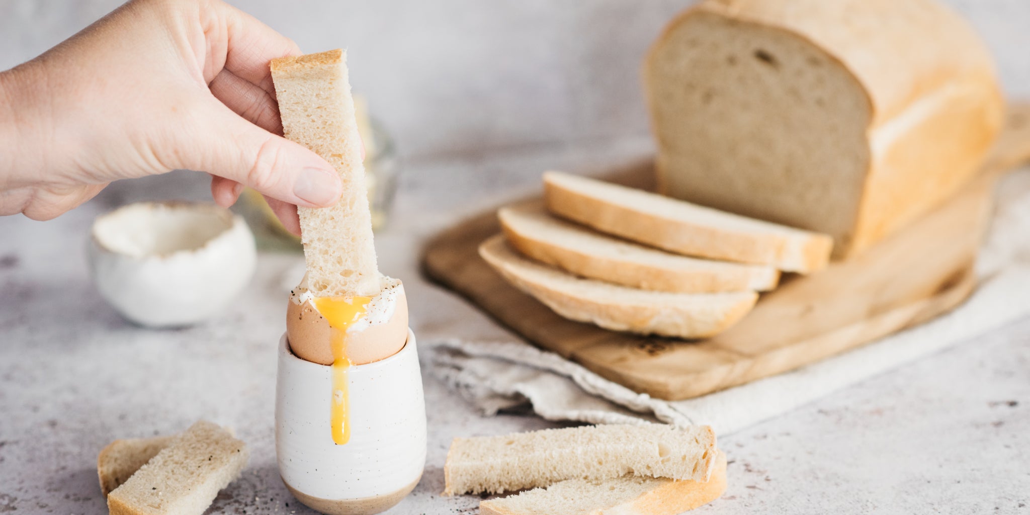 Dipping a white bread soldier into a runny boiled egg