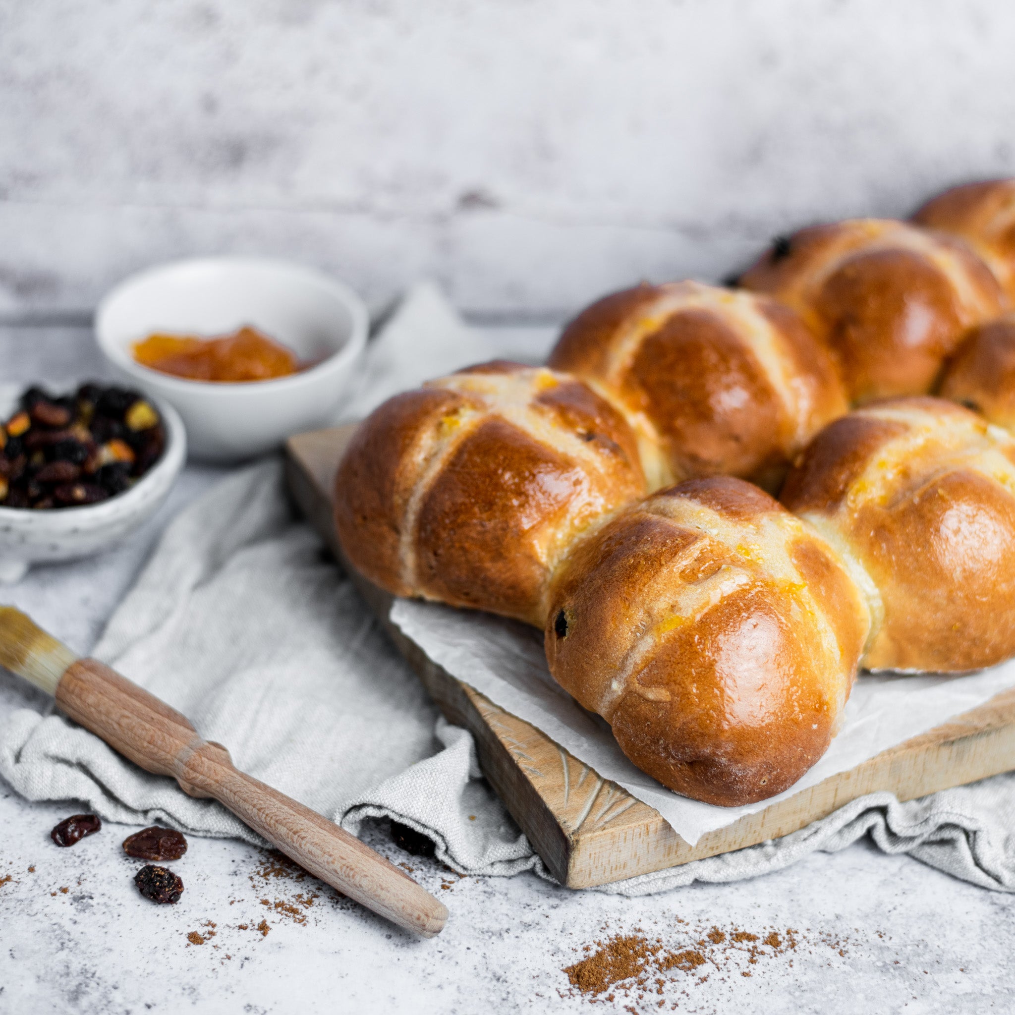 Batch of freshly-baked hot cross buns on a wooden chopping board