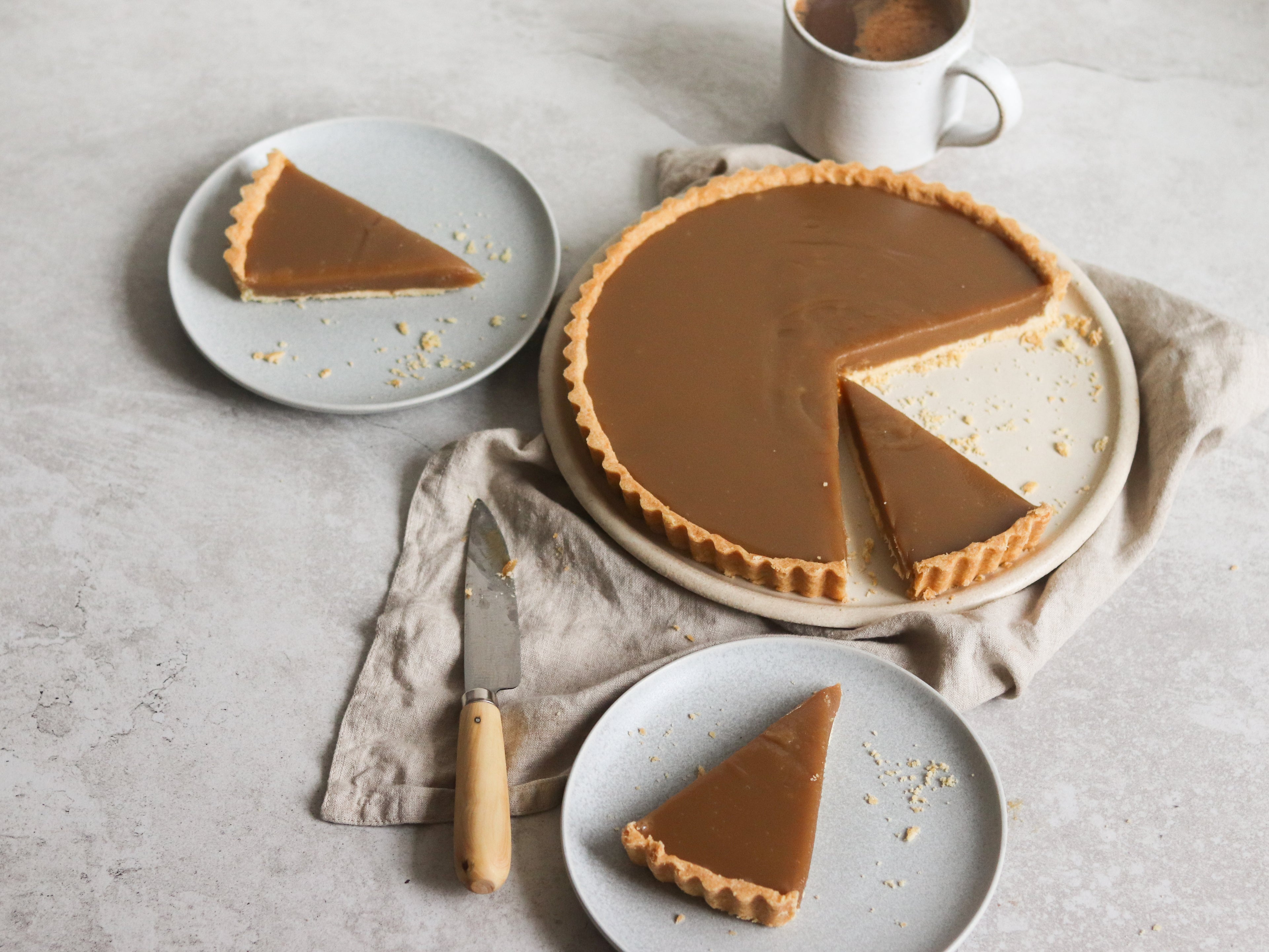 Slices of Butterscotch Tart sliced up onto plates, lay on top of linen