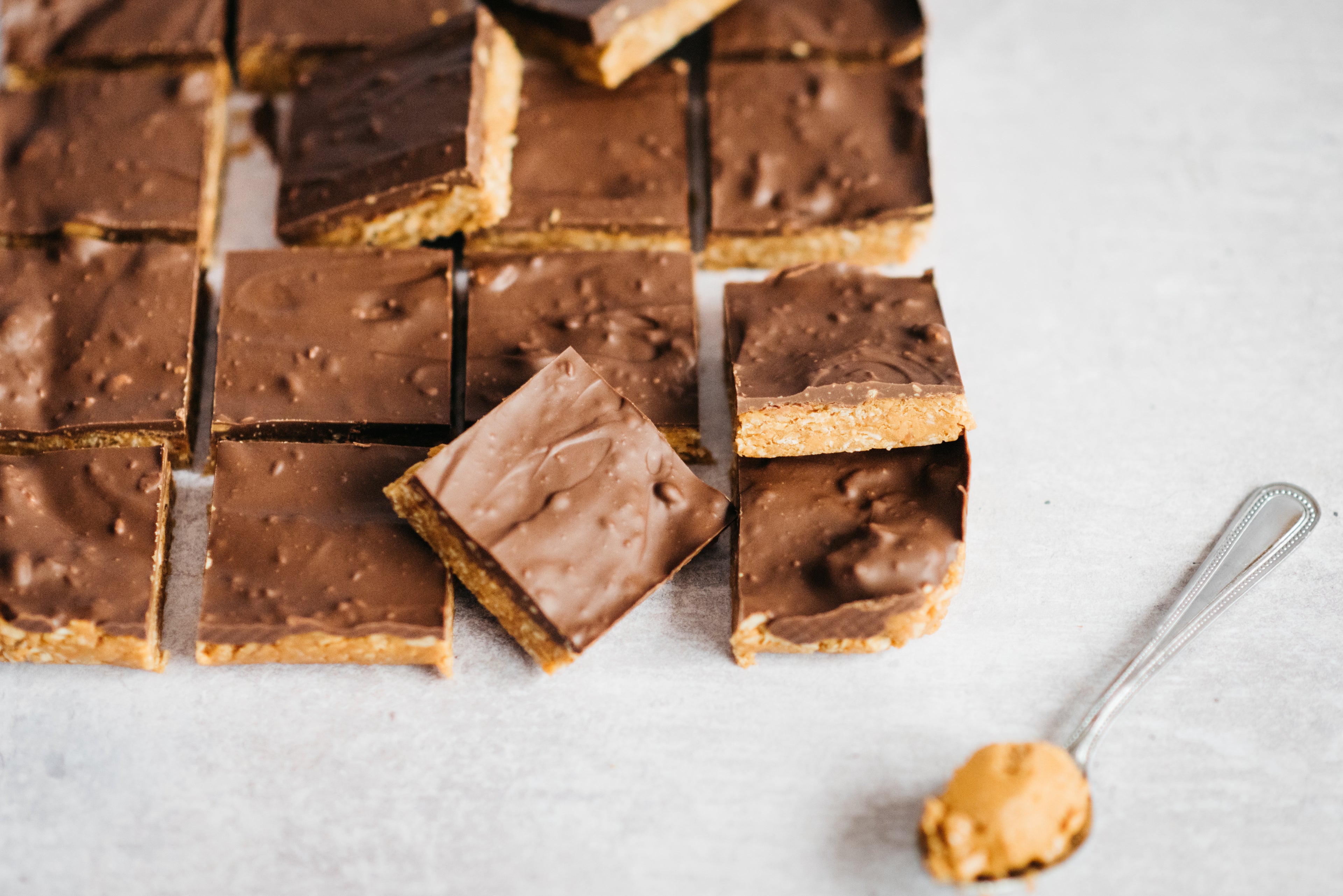 Close up of slices of Chocolate Peanut Butter Squares cut into servings, next to a spoon with a dollop of peanut butter