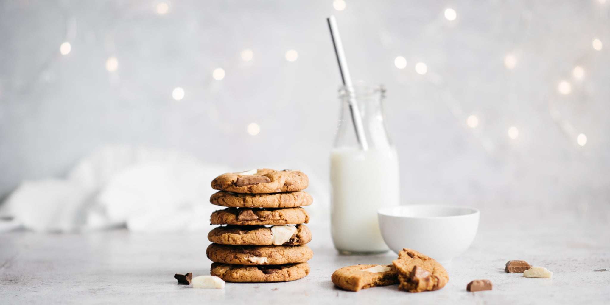 Stack of cookies in a pile with bottle of milk in background