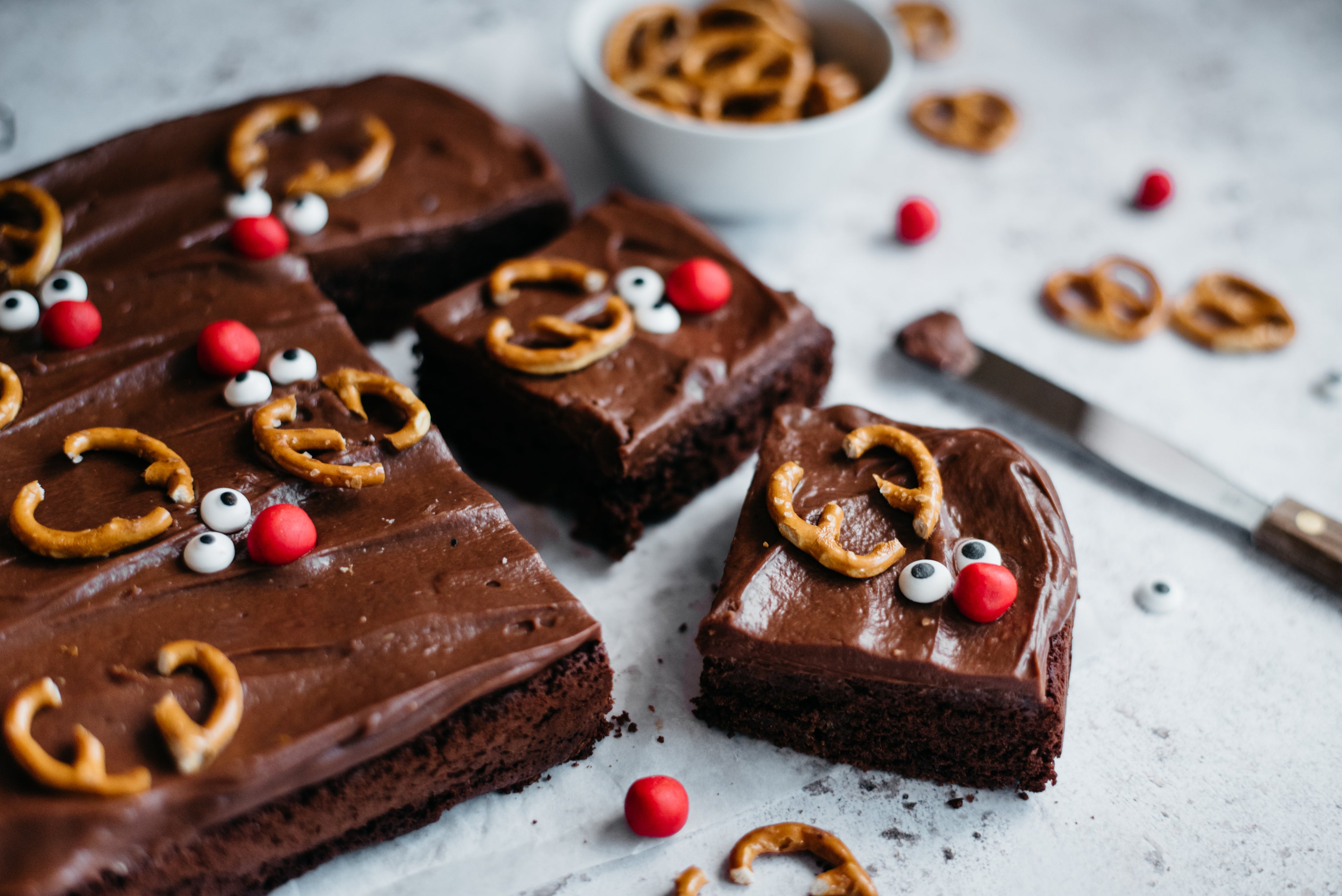 Close up of a slice of Chocolate & Caramel Reindeer Traybake decorated with pretzels 