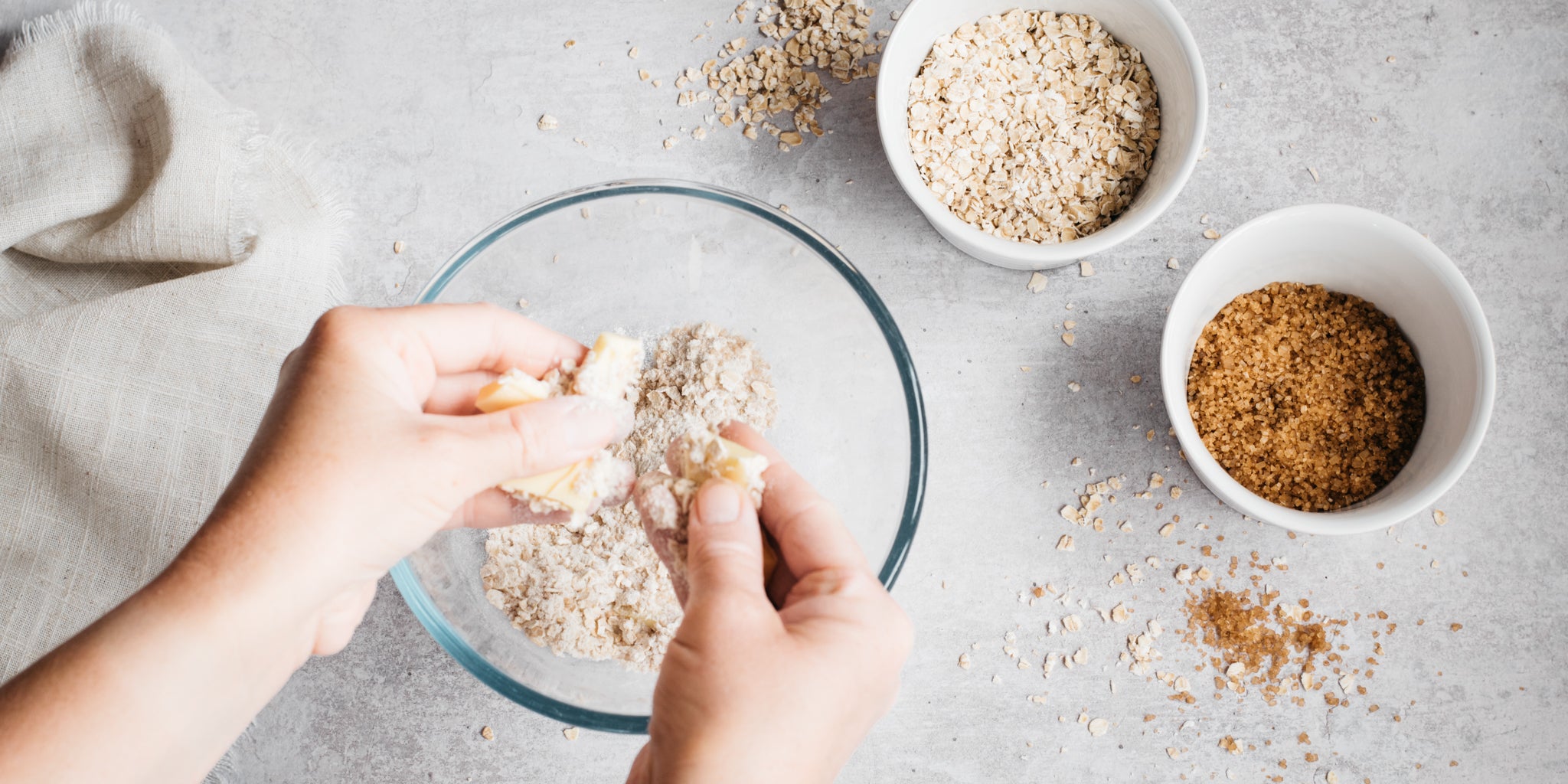 Hand crumbling butter and flour into clear bowl