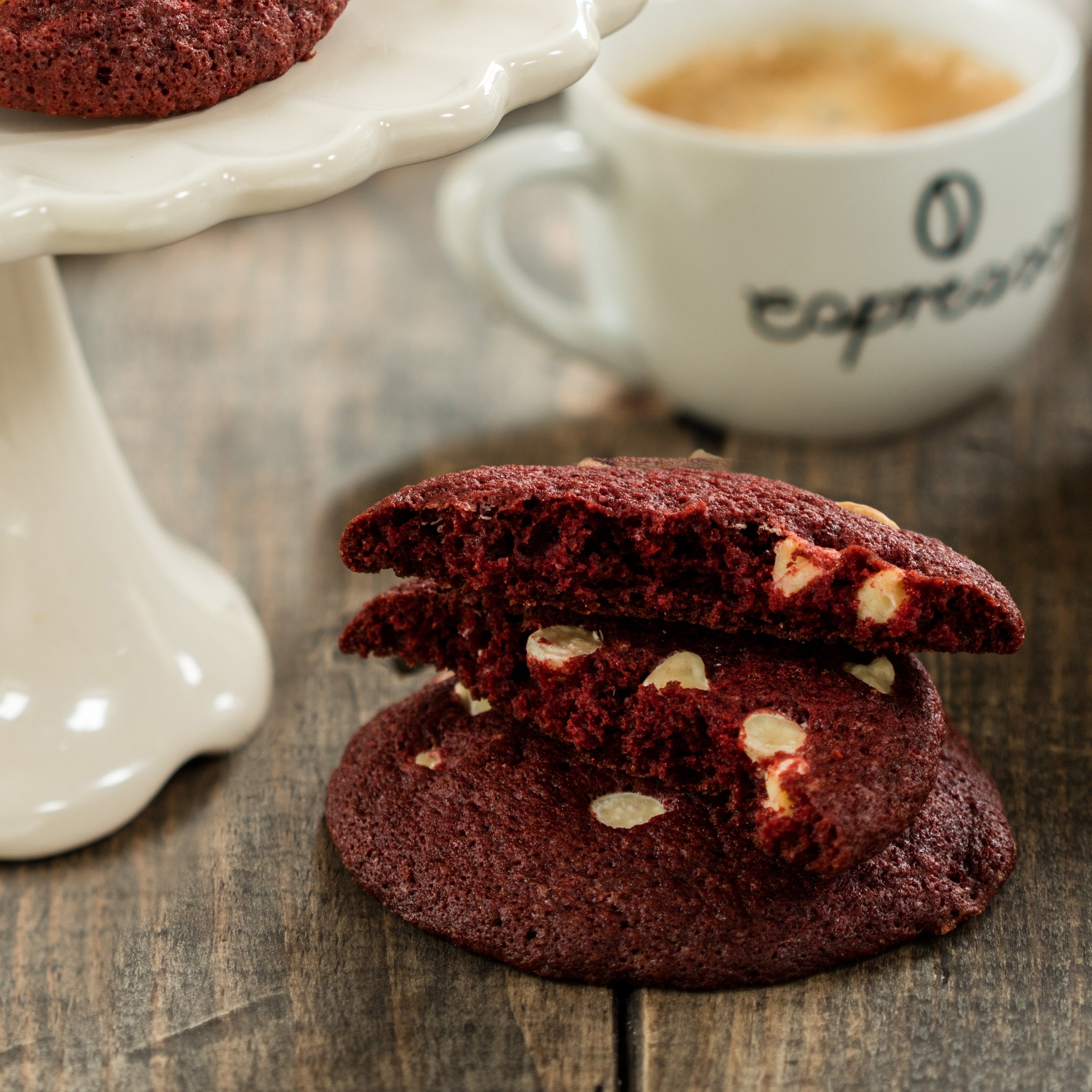 Close-up of a red velvet cookie split in half, showing its dark red centre with white chocolate chips