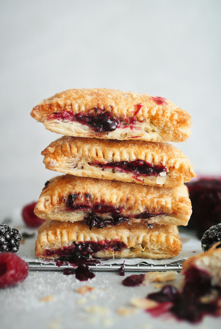 Close up of a stack of freshly baked vegan Mixed Berry Parcels with the berry insides oozing out of the plant based pastry