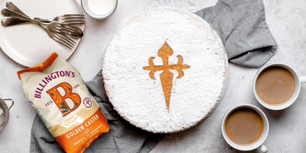 A bag of Billington's Golden Caster Sugar next to a Tarta de Santiago shot from above with a couple of mugs of coffee to the right.