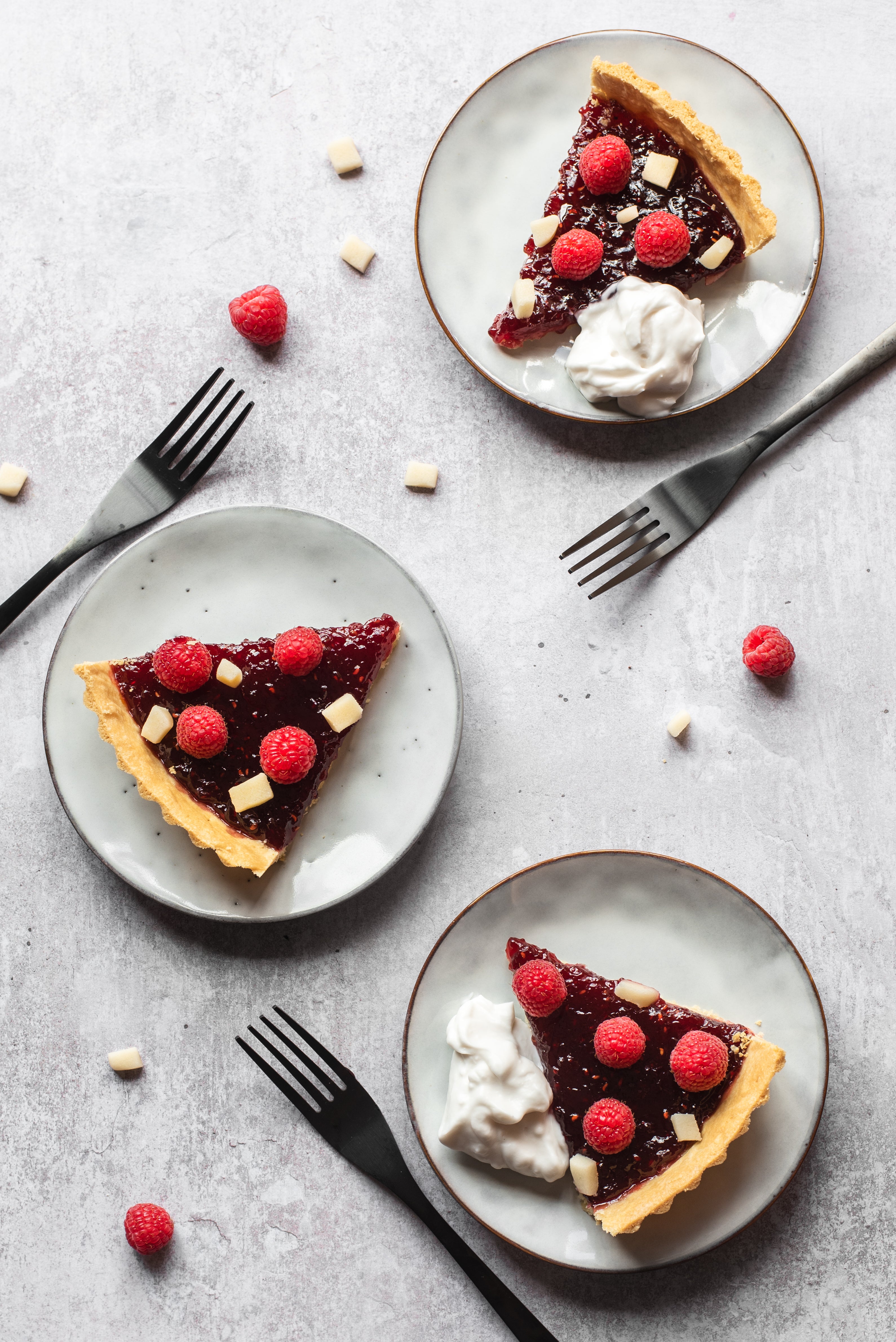 3 slices of a jam tart topped with raspberries