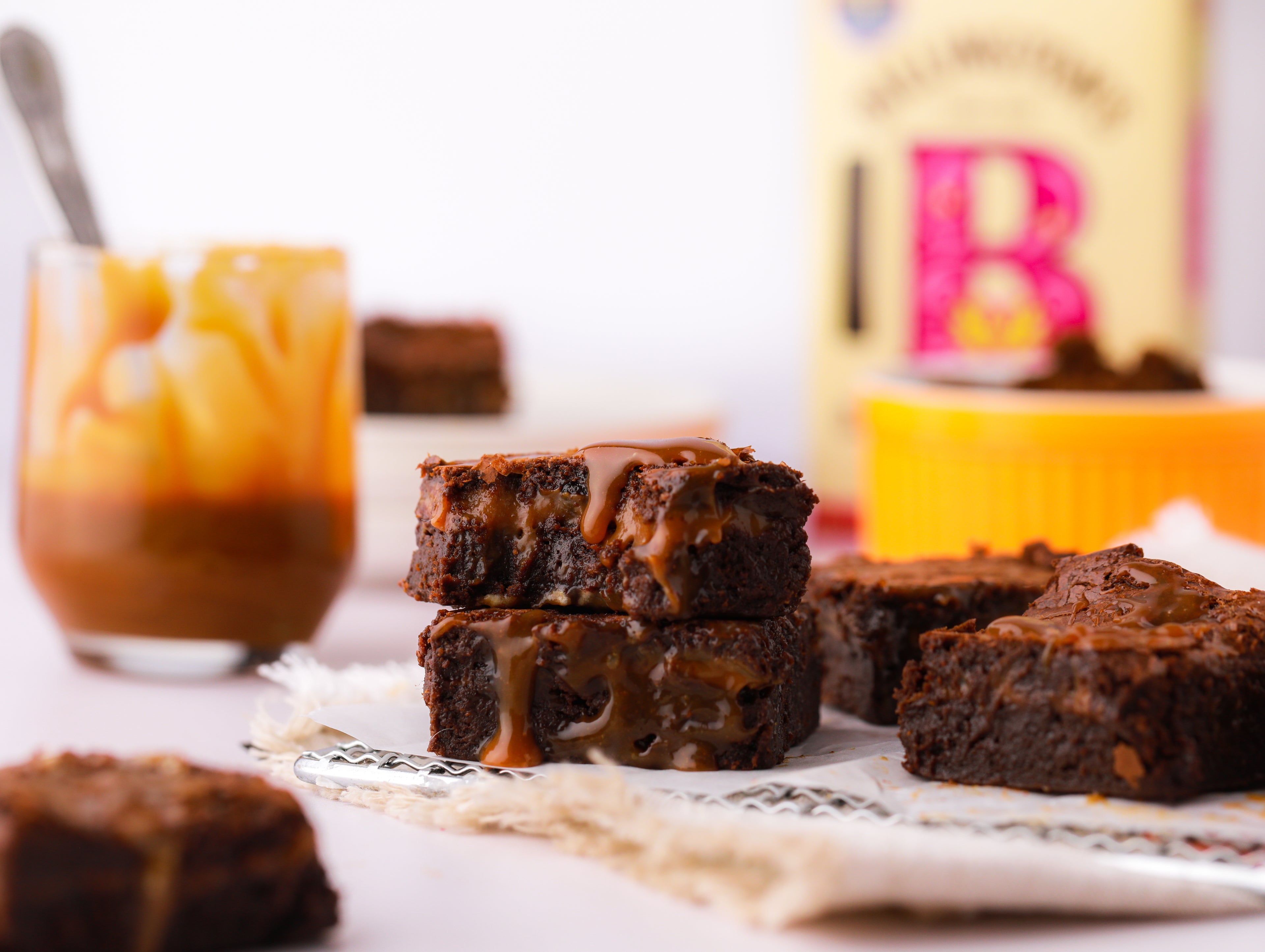 Caramel brownies with sugar pack and jar of caramel with spoon in background