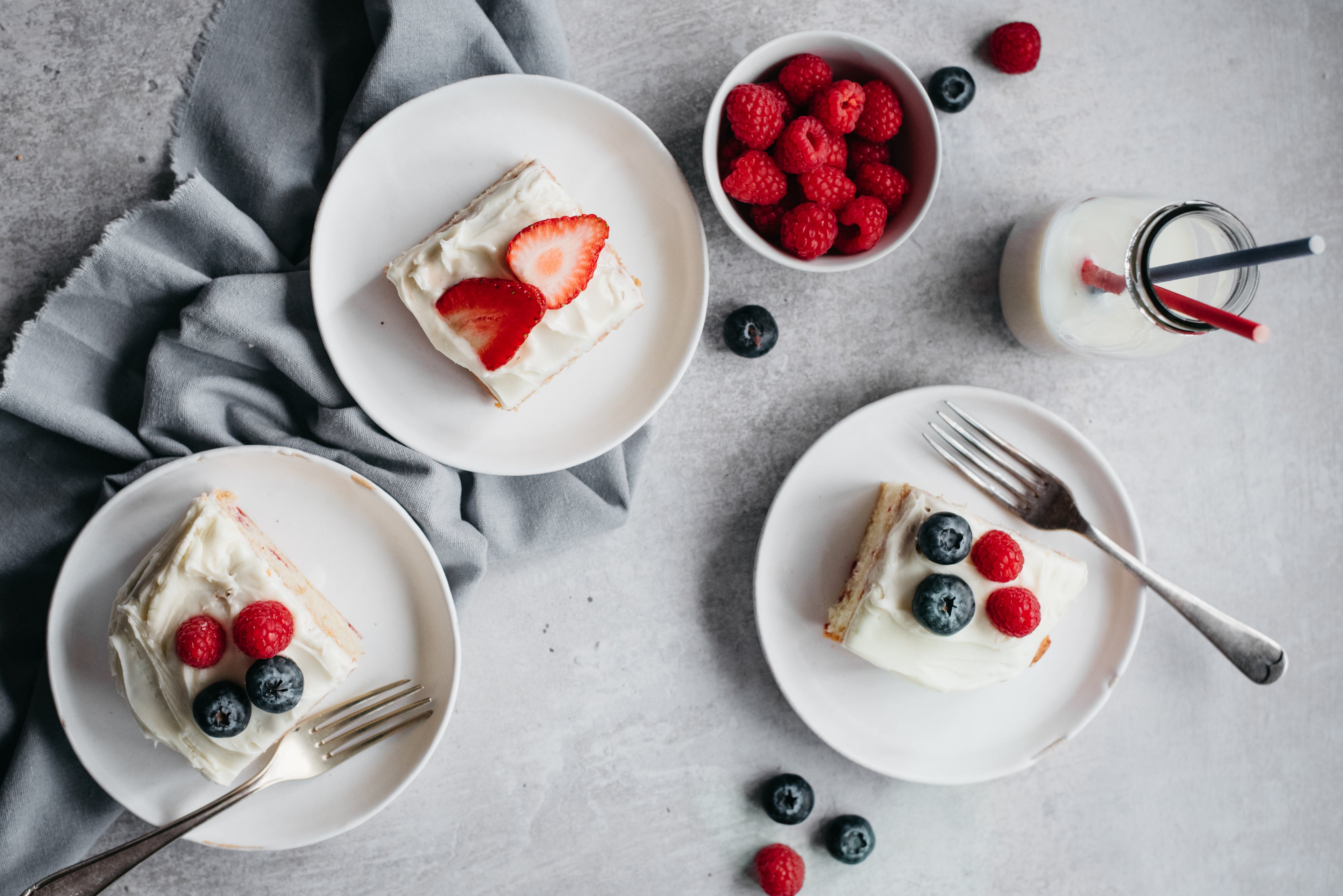 Union Jack Traybake sliced into portions served on plates next to forks, with the cake topped with fresh seasonal berries perfect for a summer Jubilee party