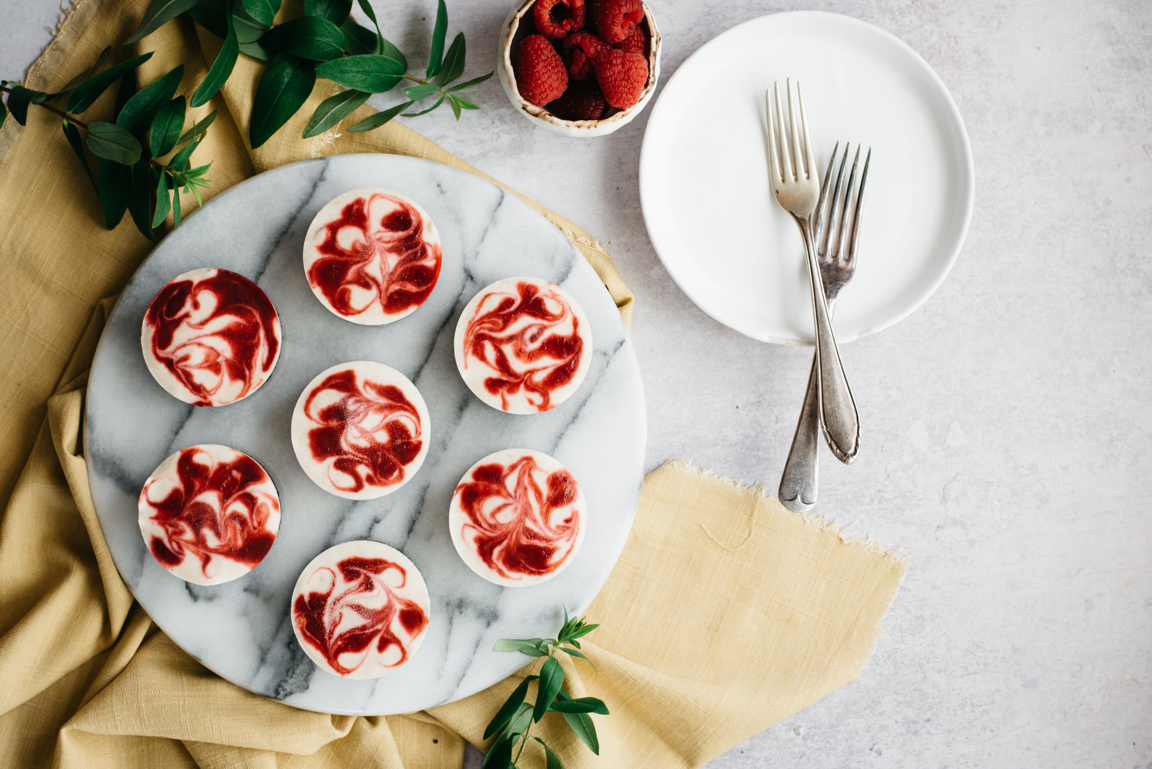 Top down view of a plate of vegan raspberry and banana cheesecake cups