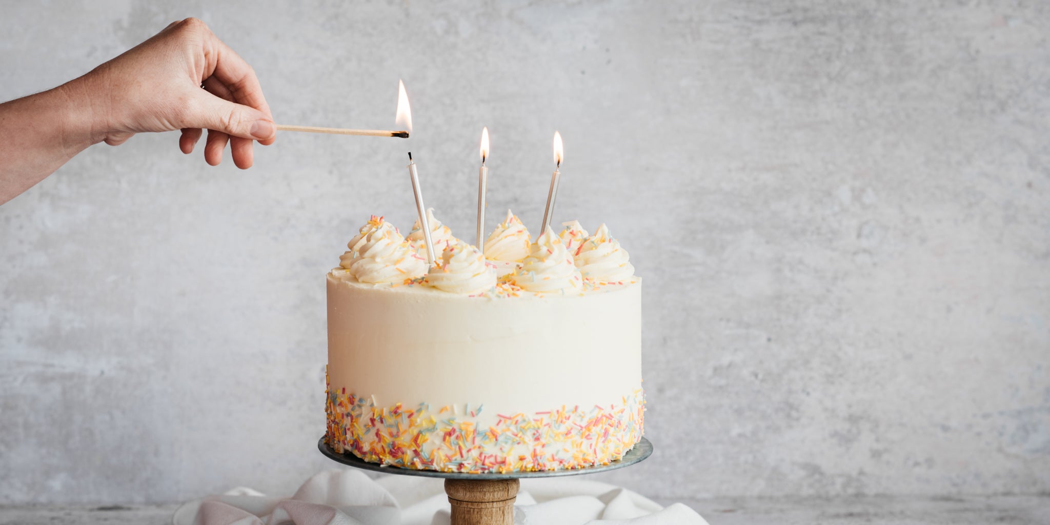 Vegan Vanilla Cake with metallic candles ontop being lit ready to blow out for a Birthday