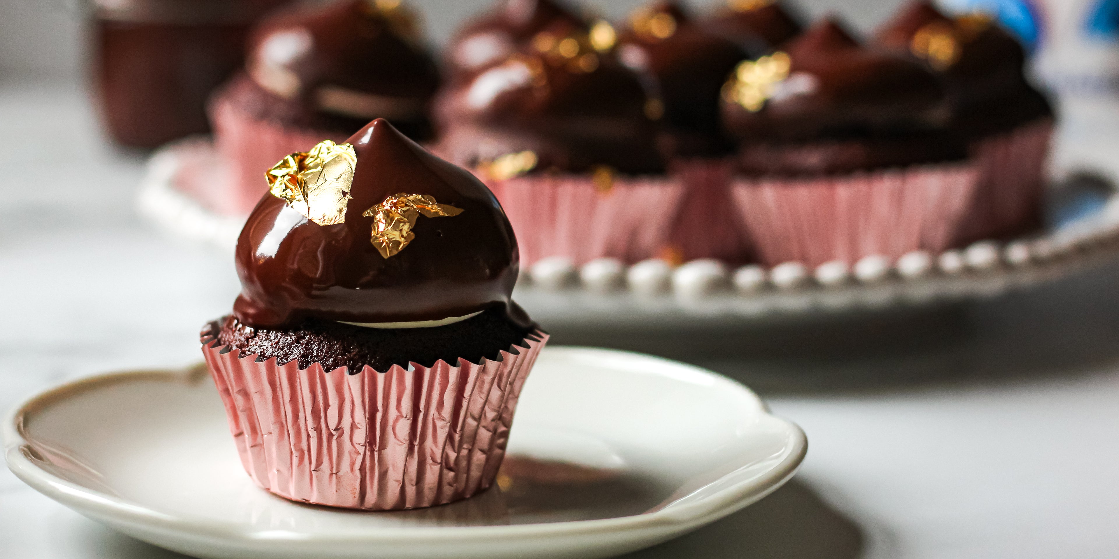 Hi-Hat Cupcake close up, showing the glossy chocolate dip, and gold leaf decoration