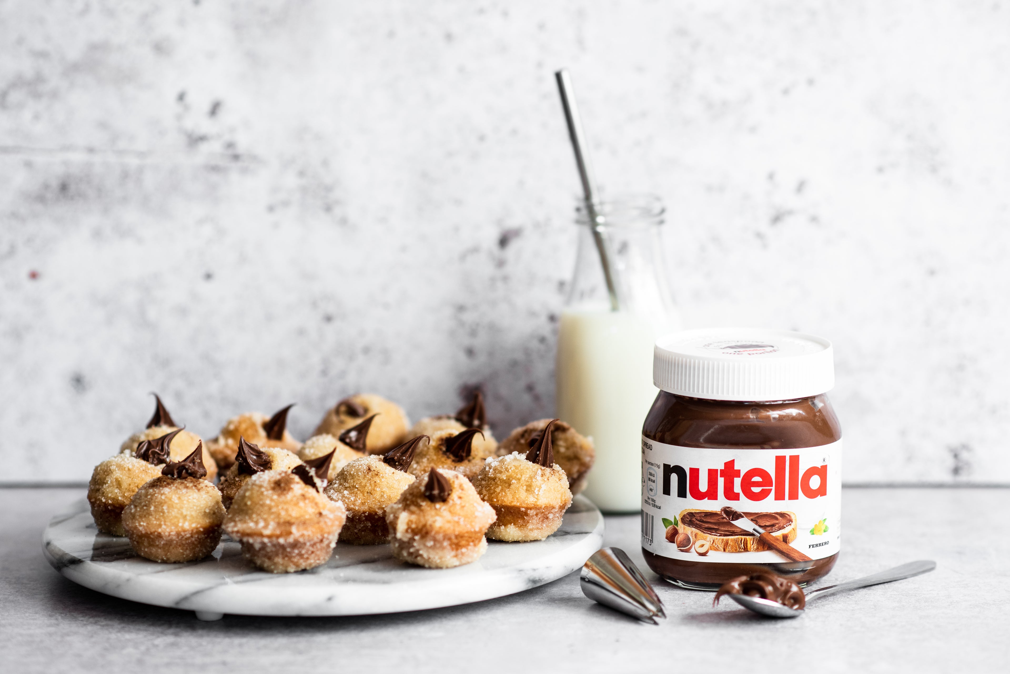 Plate of Nutella filled doughnuts next to a jar of Nutella