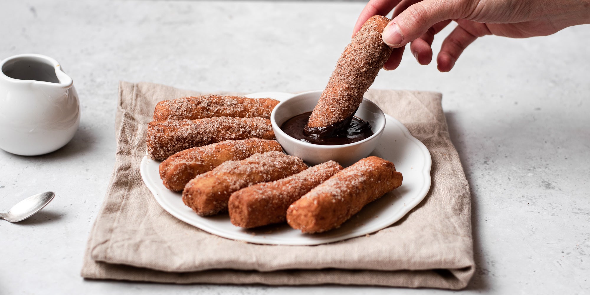 Doughnut Sticks with hand, being dipped into Chocolate Dip
