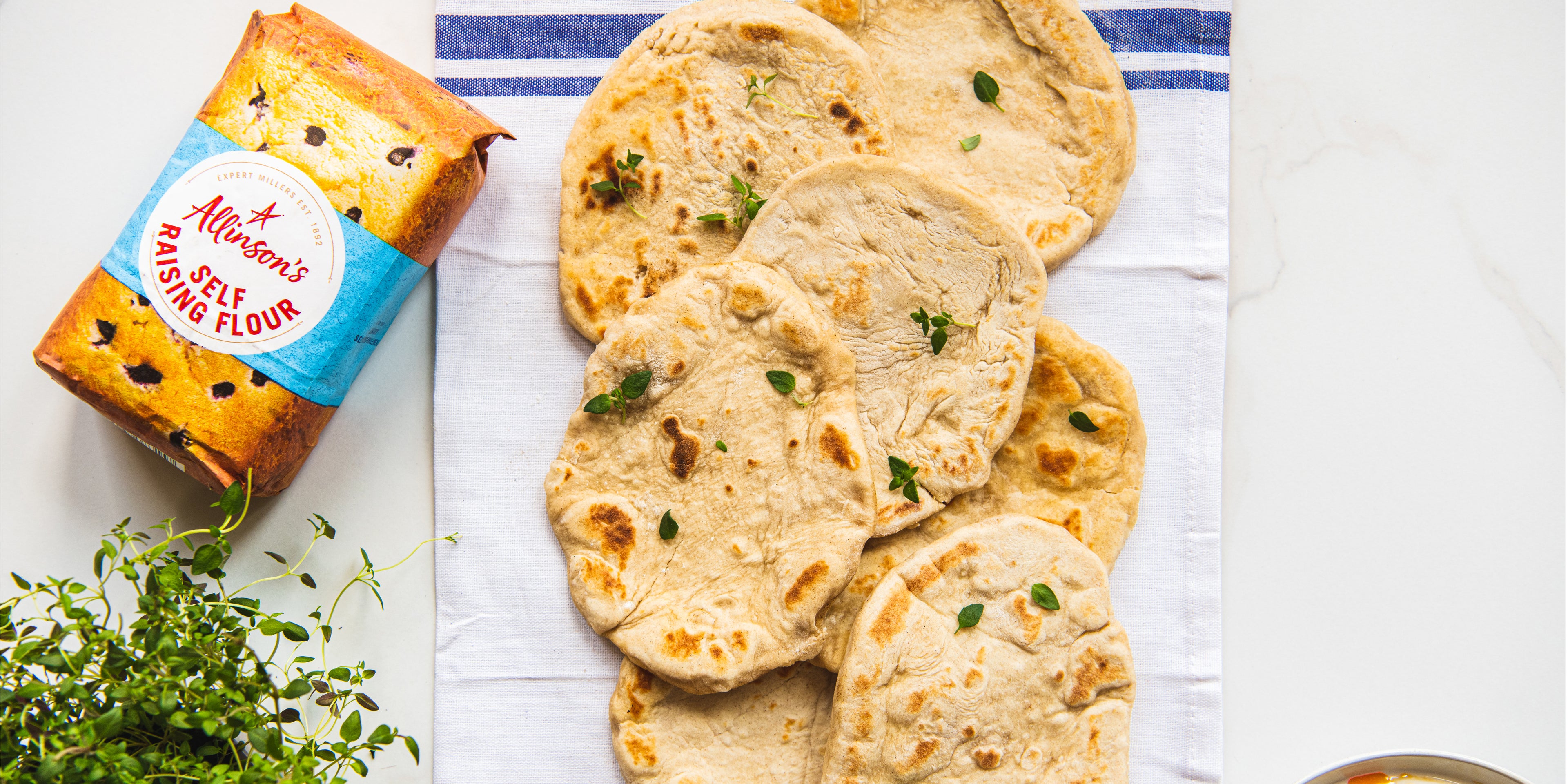 Top down view of a plate of kefir flatbreads next to a packet of Allinson's self raising flour