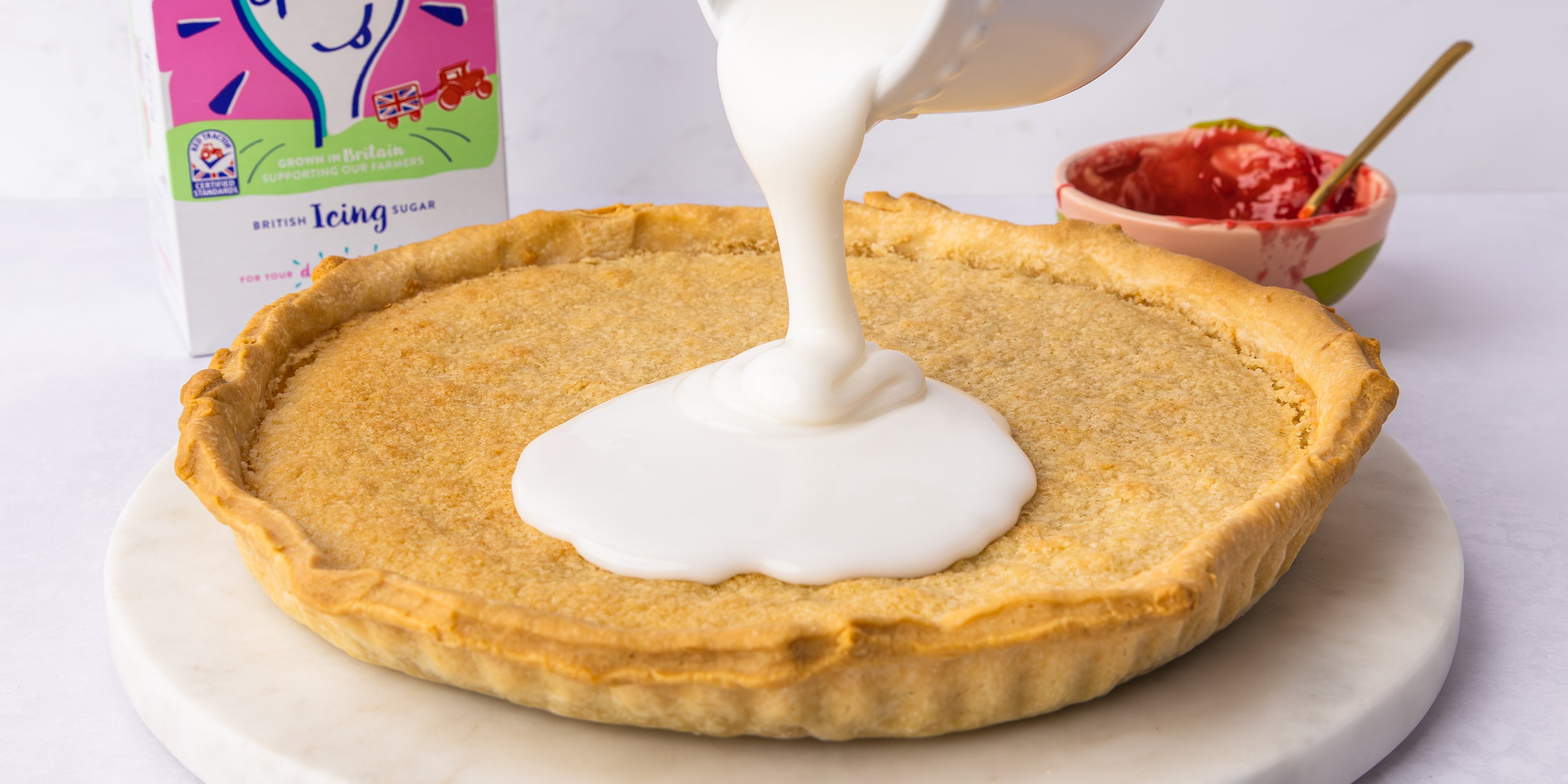 Icing being poured on top of a bakewell tart