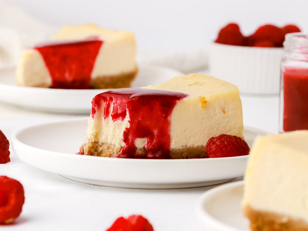 Slice of homemade baked cheesecake with a fruity raspberry topping