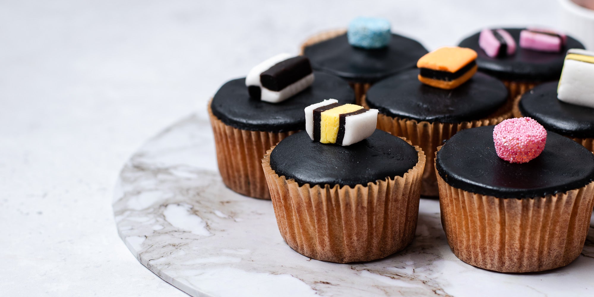 Cupcakes in brown cases, black fondant, topped with liquorice allsorts