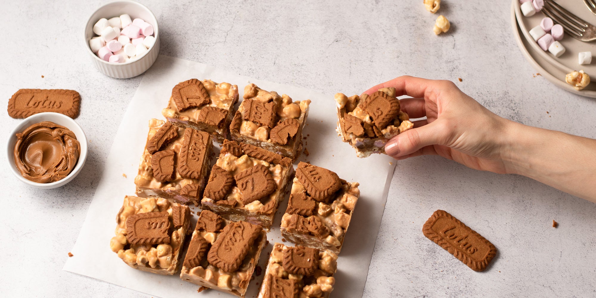 Biscoff rocky road sliced into 9 pieces with a hand taking one slice