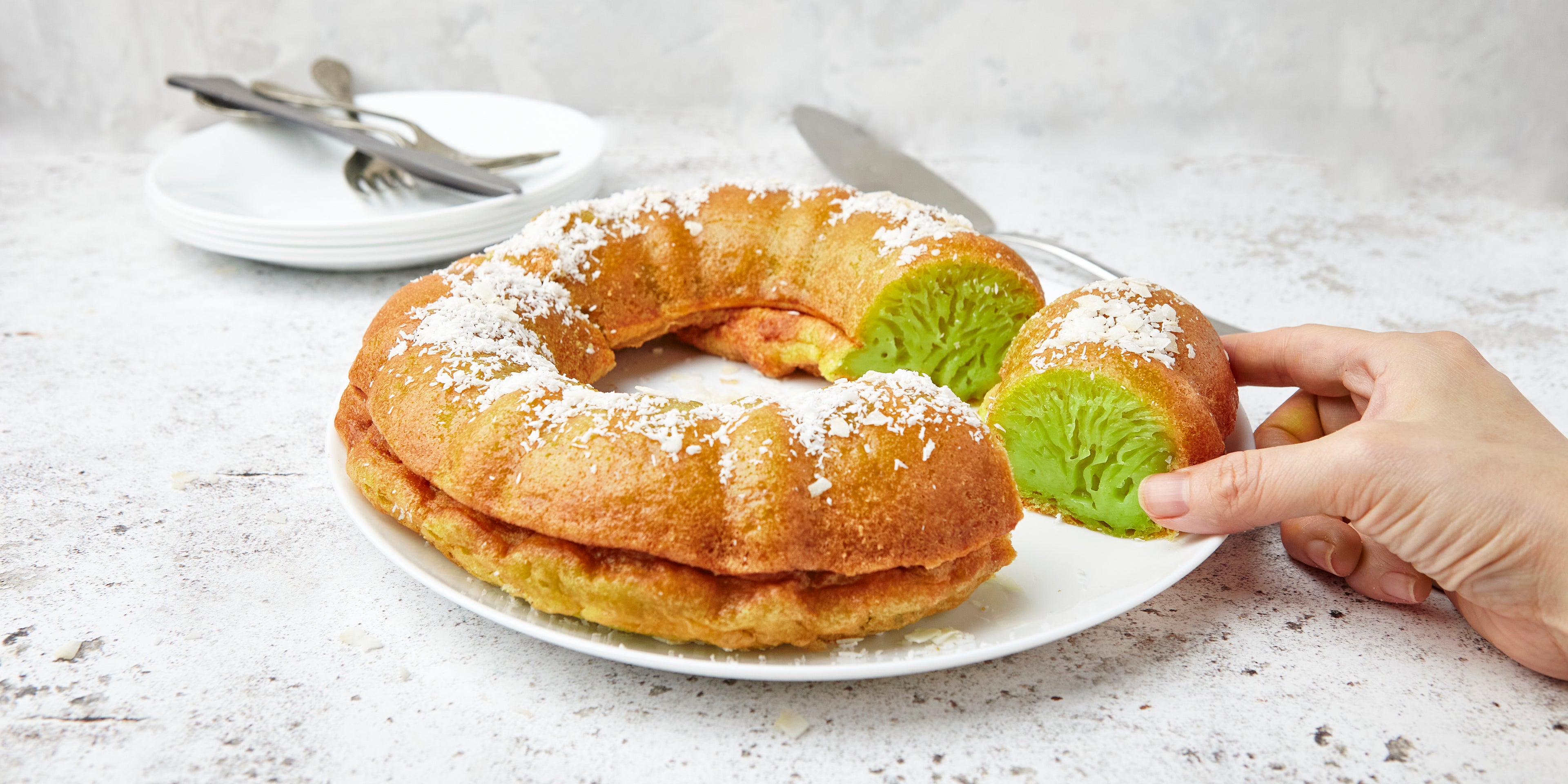 Vietnamese Honeycomb Cake with a slice cut out of it, with hands reaching for a piece. Filled with pandan extract.