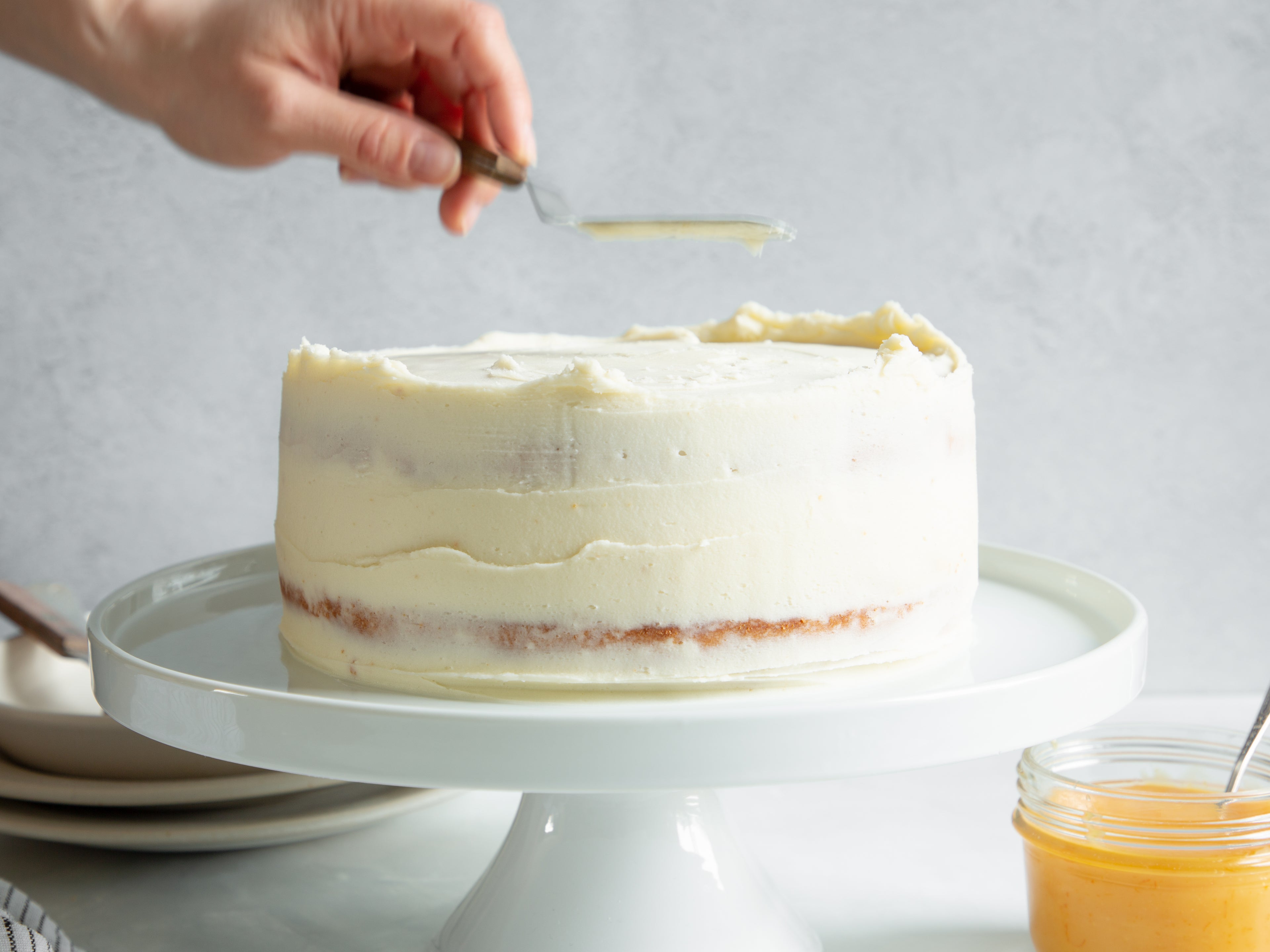 Close up of a Classic Lemon Cake being decorated with a hand using an offset spatula using Silver Spoon Icing Buttercream