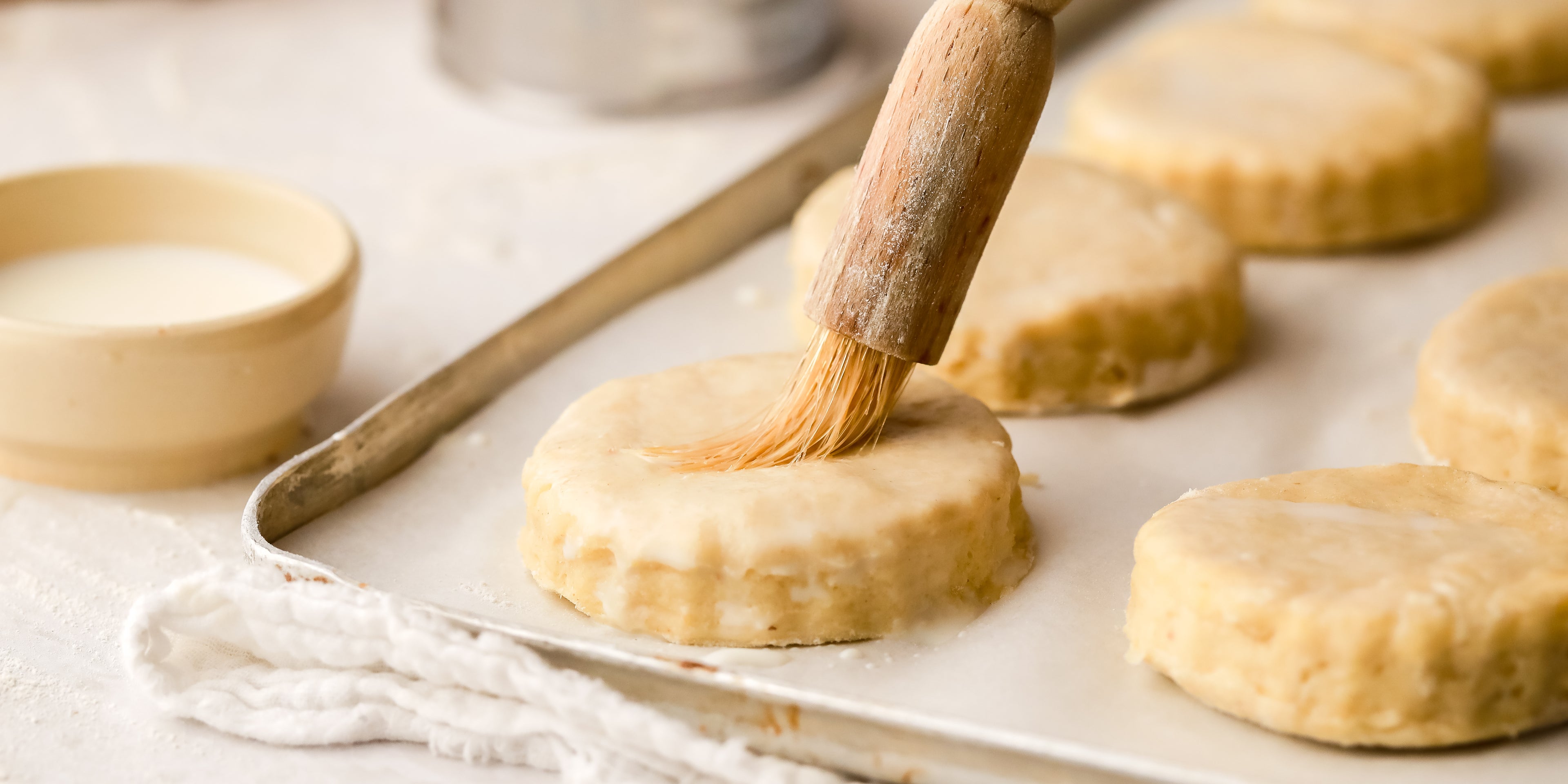 Rounds of scone dough being brushed with milk