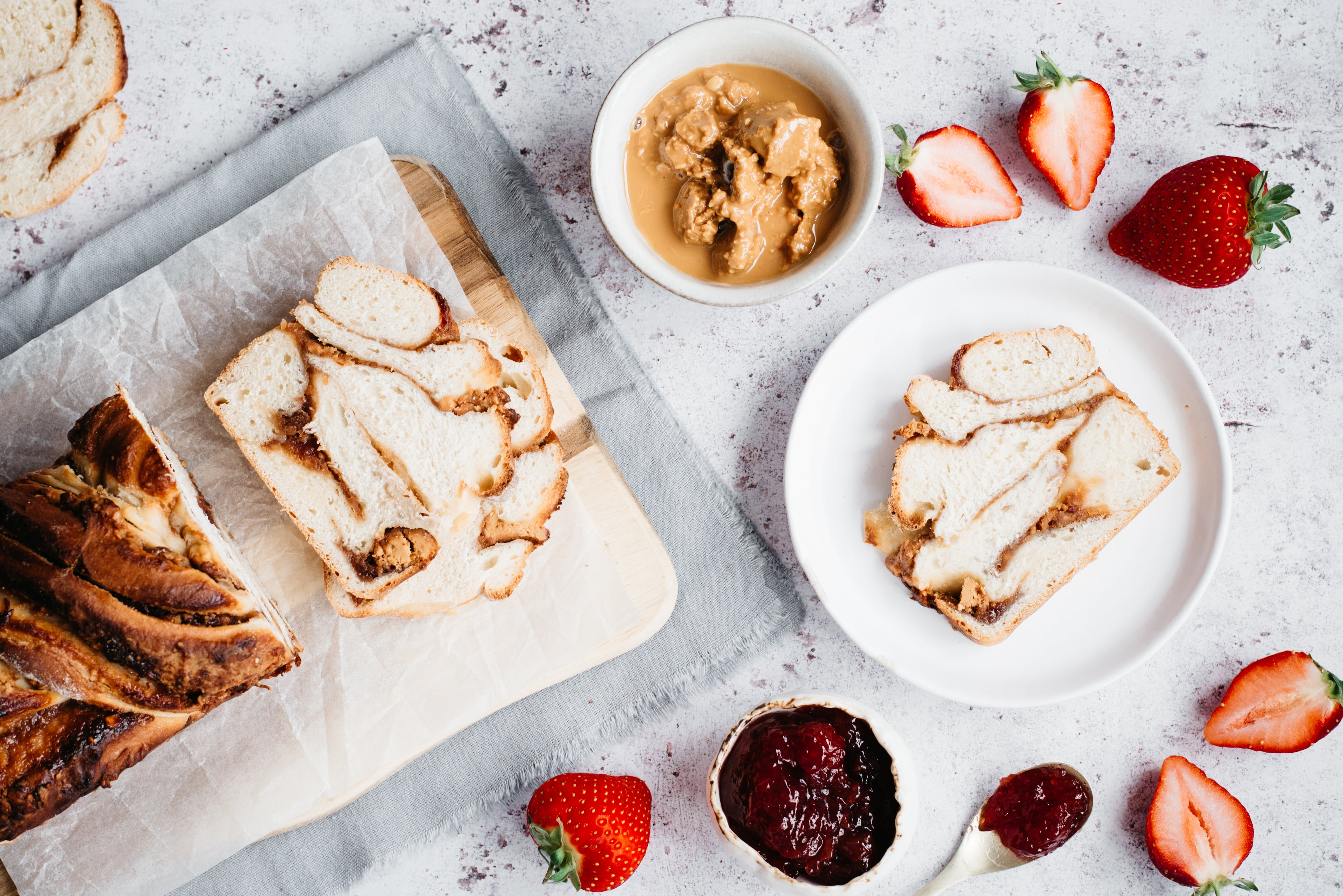 Peanut Butter Jam Babka sliced with spoon of jam and chopped strawberries