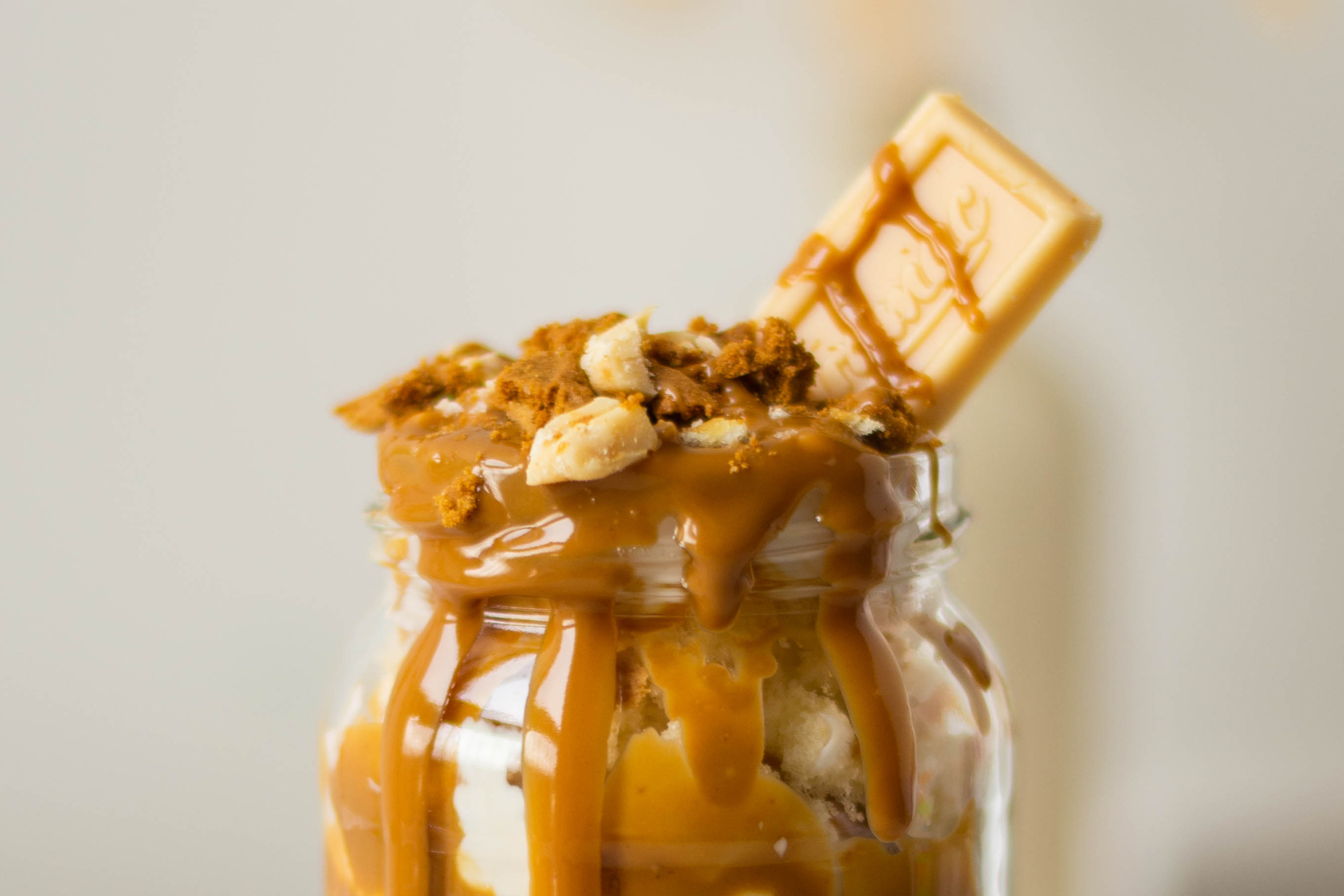 Close up of the top of a Biscoff & Caramac Cake Jar with Caramac pieces and drizzles of Biscoff spread