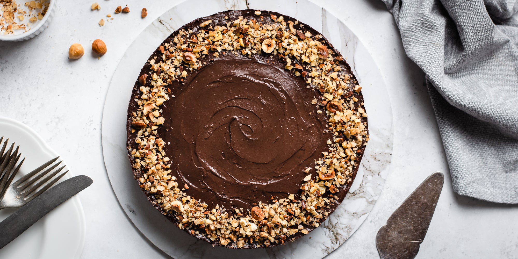 Top view of Raw Chocolate Avocado Cheesecake on a marble serving board next to a cake knife