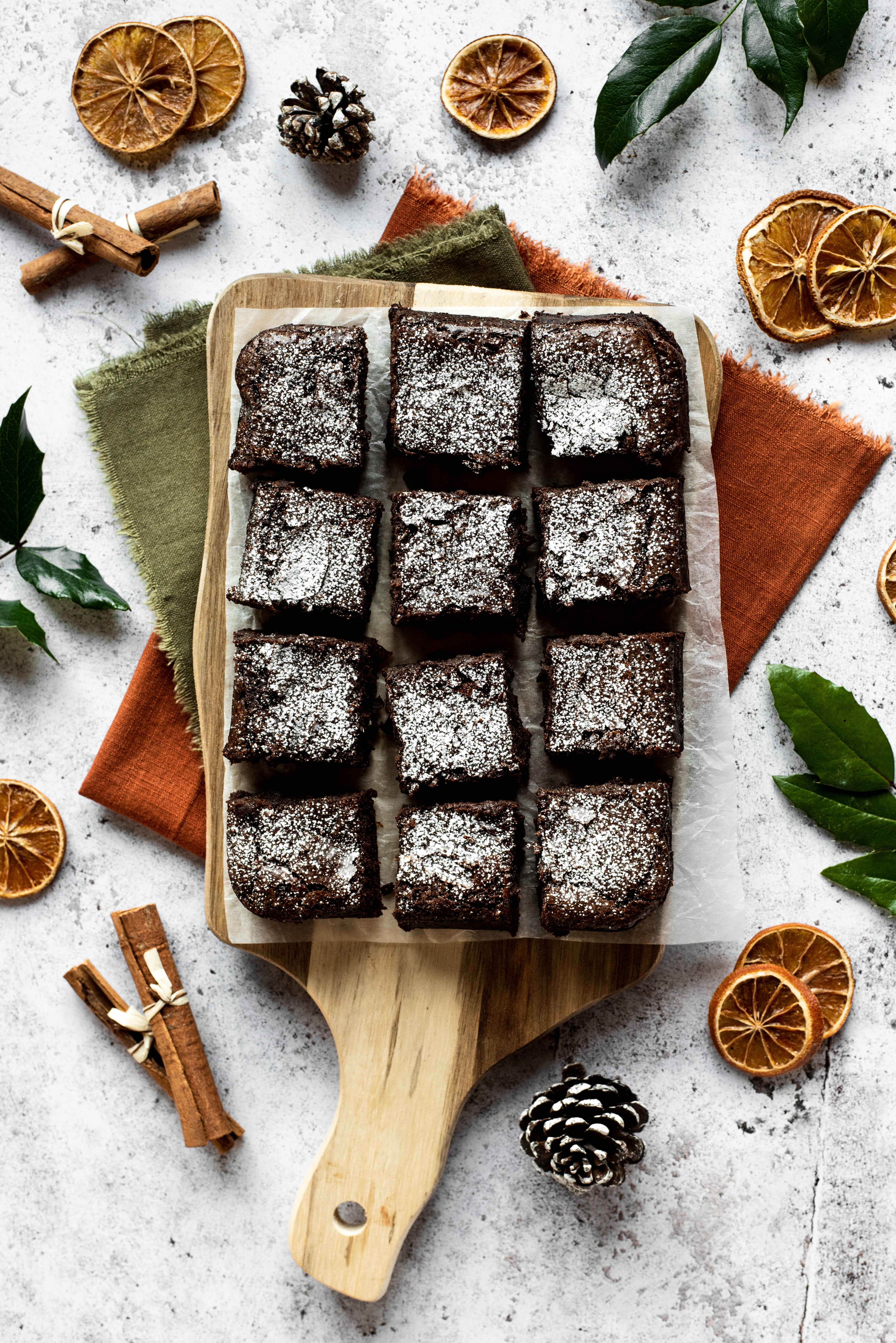 12 square chocolate brownies arranged on a wooden chopping board